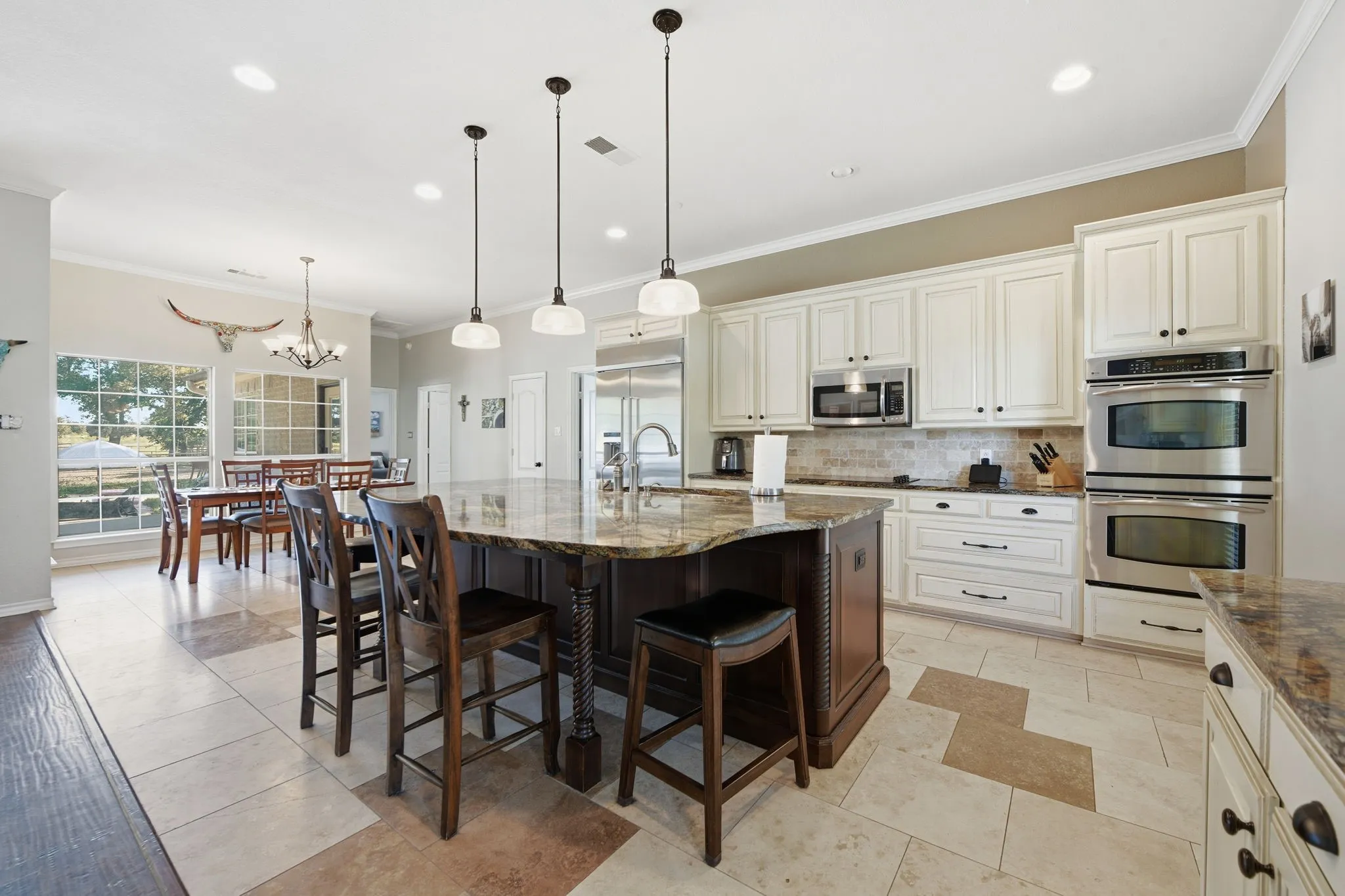 Kitchen featuring crown molding, tasteful backsplash, hanging light fixtures, appliances with stainless steel finishes, and dark stone countertops