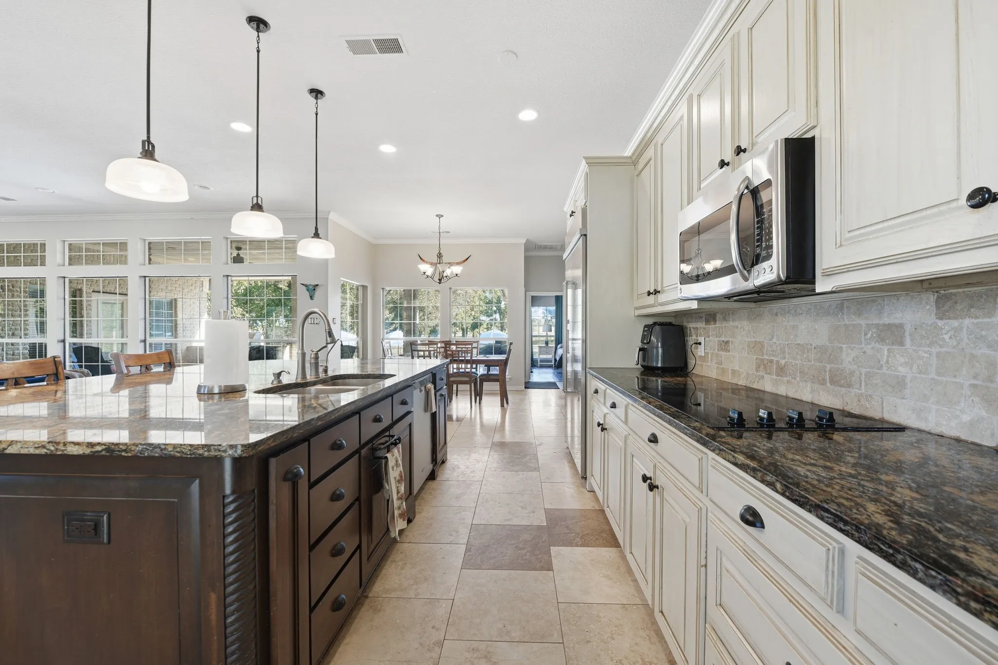 Kitchen with ornamental molding, dark stone counters, decorative light fixtures, decorative backsplash, and appliances with stainless steel finishes