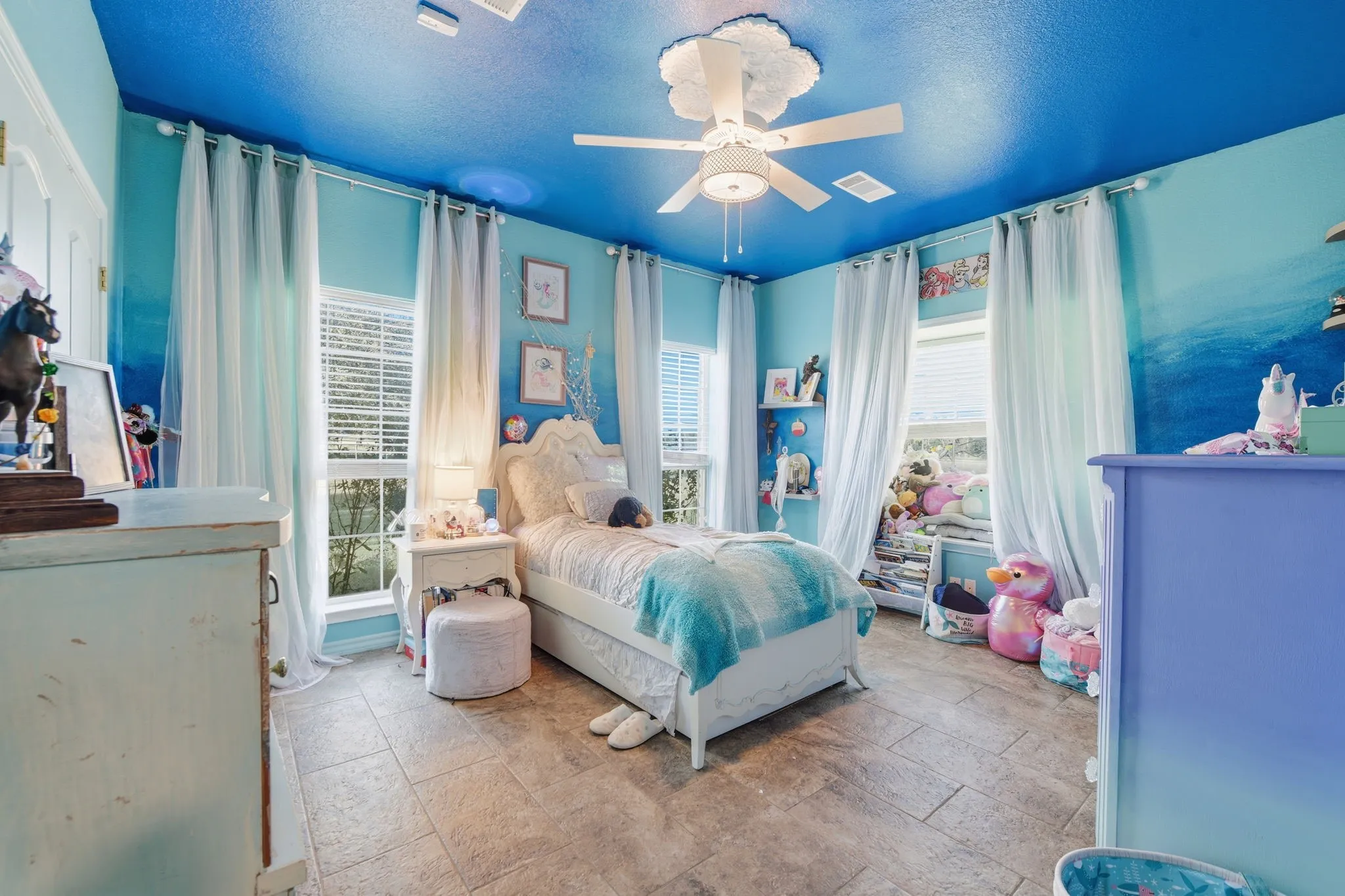 Bedroom with a textured ceiling, ceiling fan, and stone finish floors