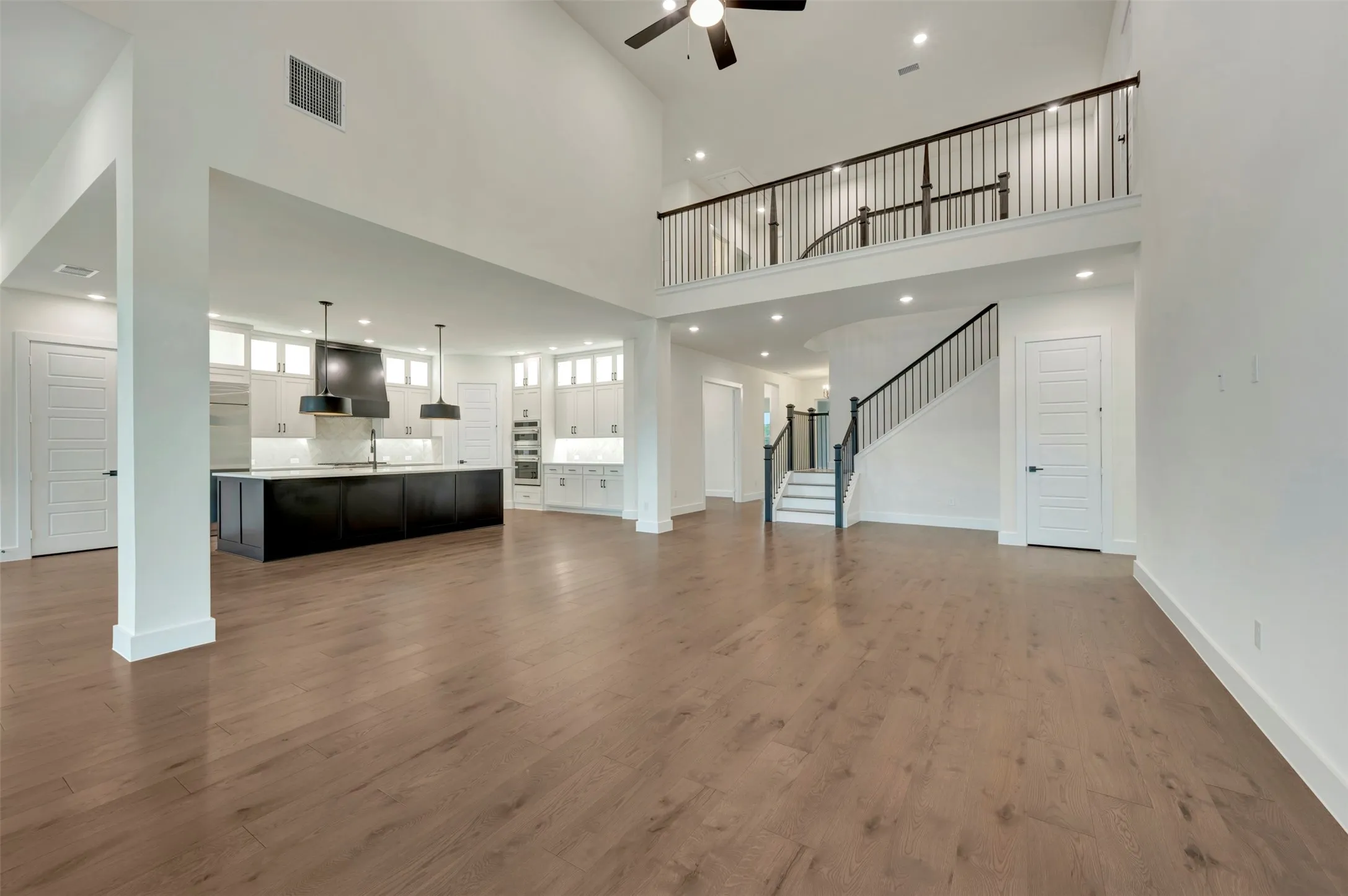 Living room with a ceiling fan, wood finished floors, a high ceiling, and recessed lighting