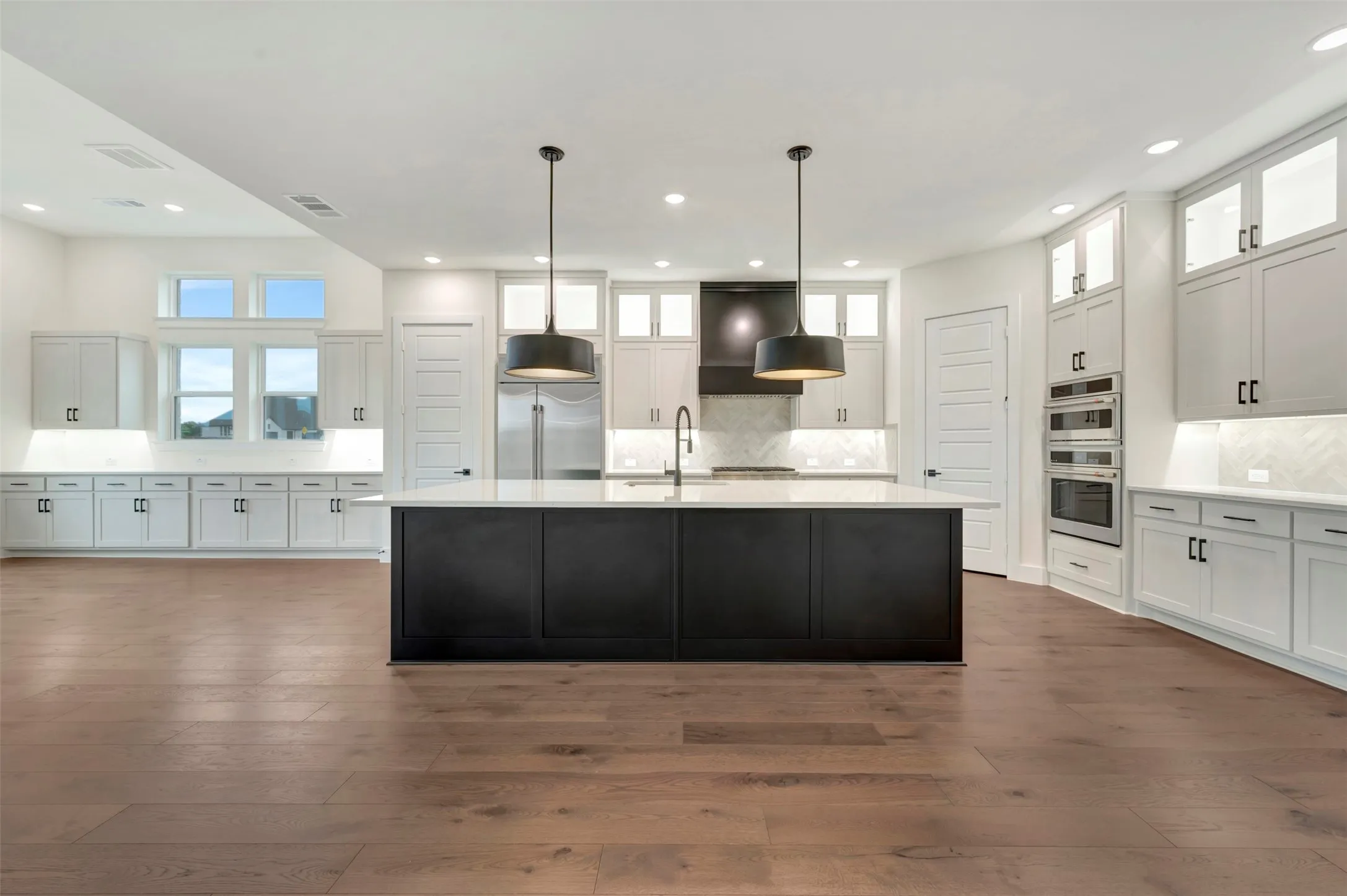Kitchen featuring glass insert cabinets, decorative backsplash, decorative light fixtures, dark wood-style flooring, and two tone cabinetry
