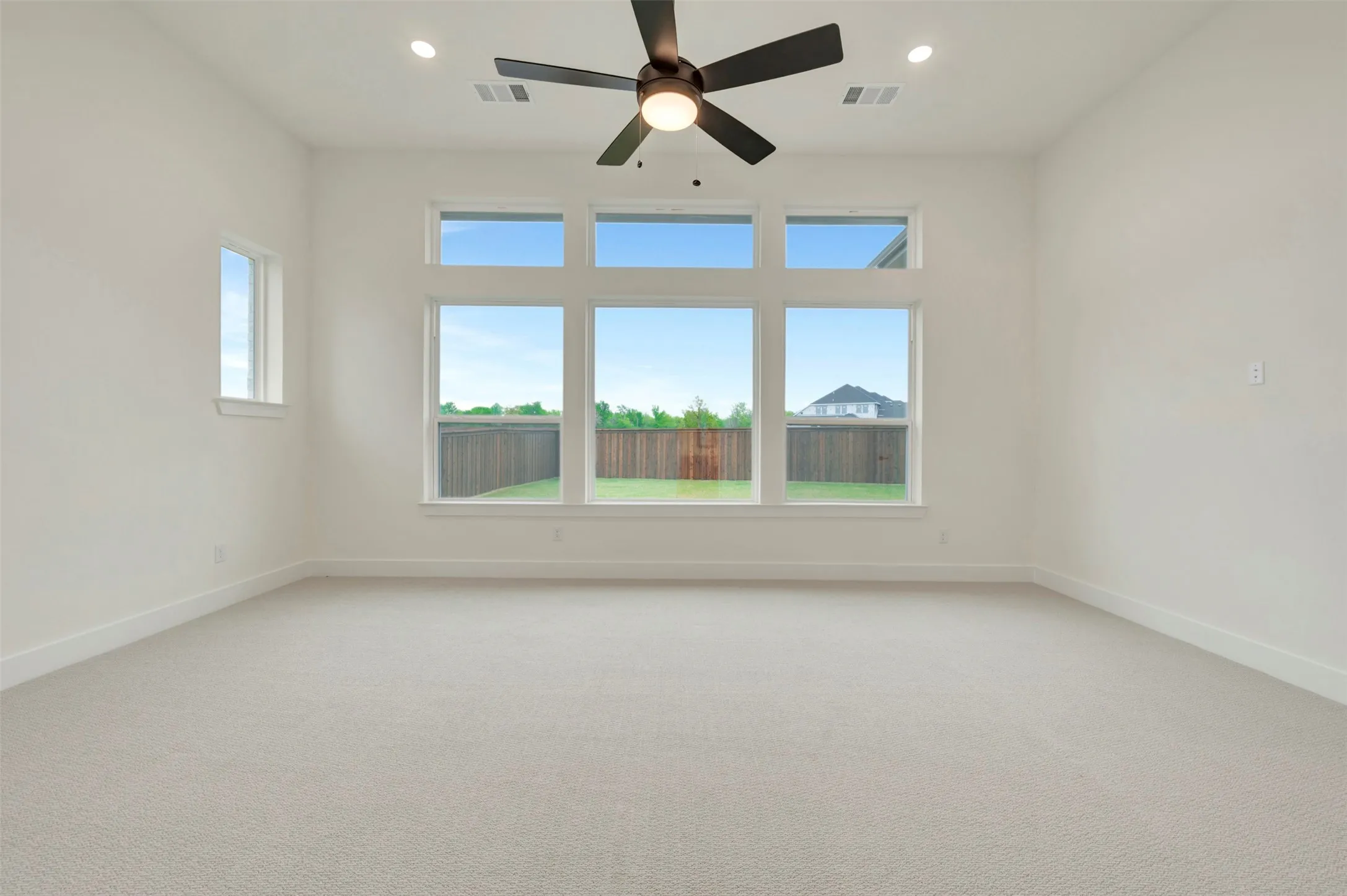 Owners Retreat with light carpet, a ceiling fan, and recessed lighting