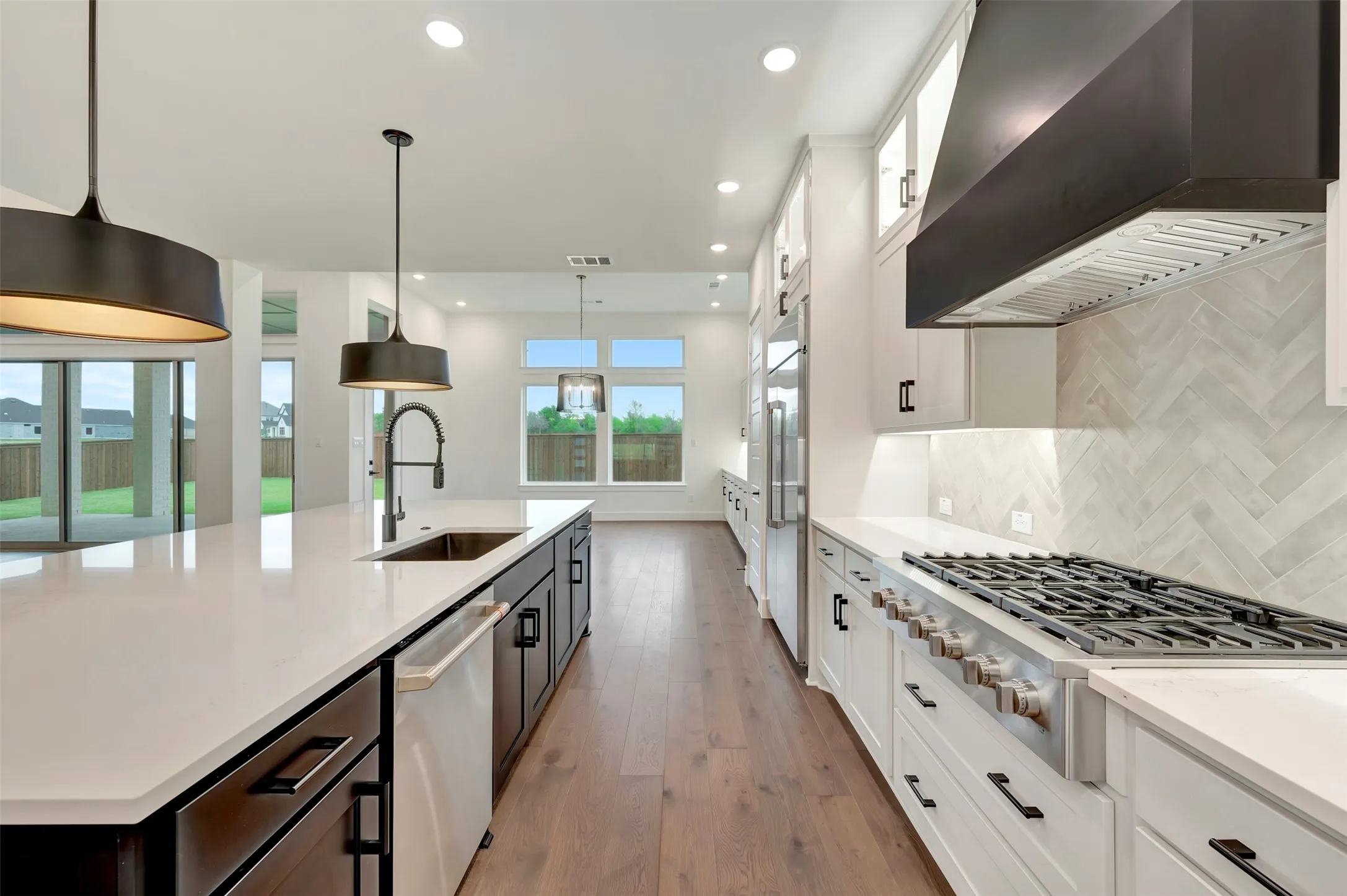 Dual tone kitchen featuring dual tone cabinetry, stainless steel appliances, a spacious island, light wood finished floors, and light stone countertops