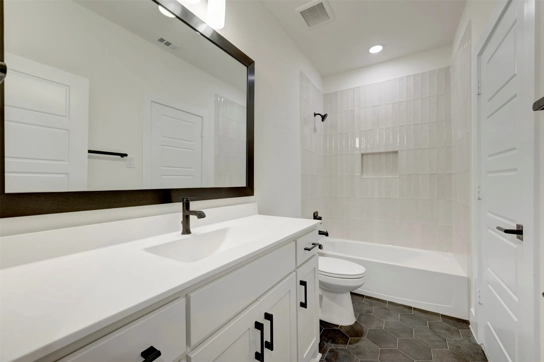 Full bathroom with vanity,  shower combination, and dark tile patterned floors
