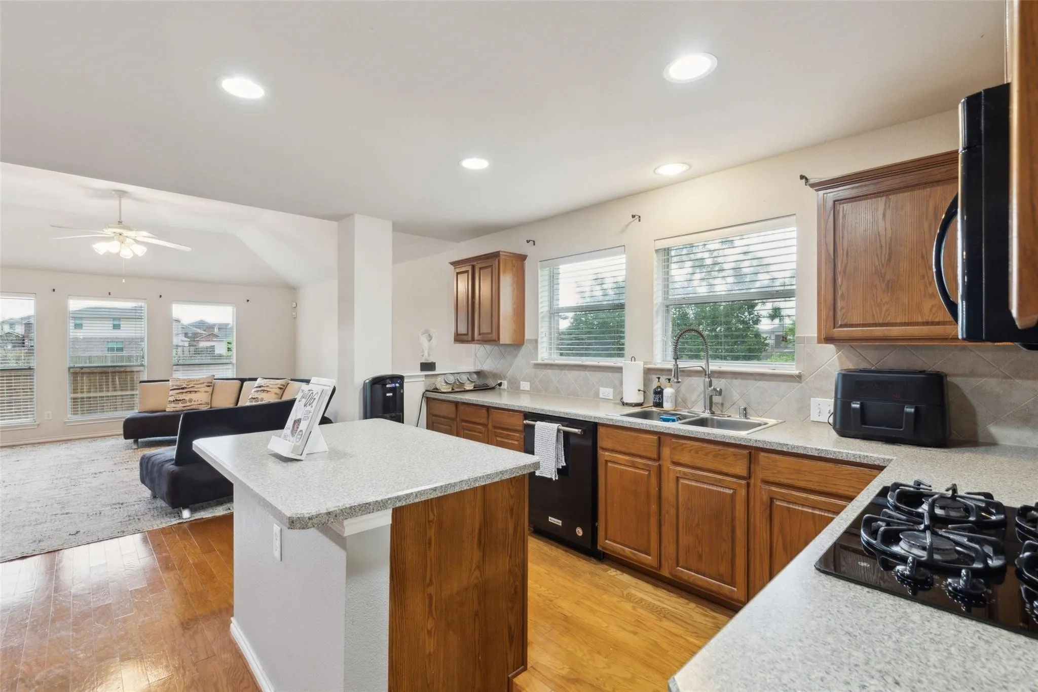 Kitchen with a center island, backsplash, brown cabinets, open floor plan, and recessed lighting