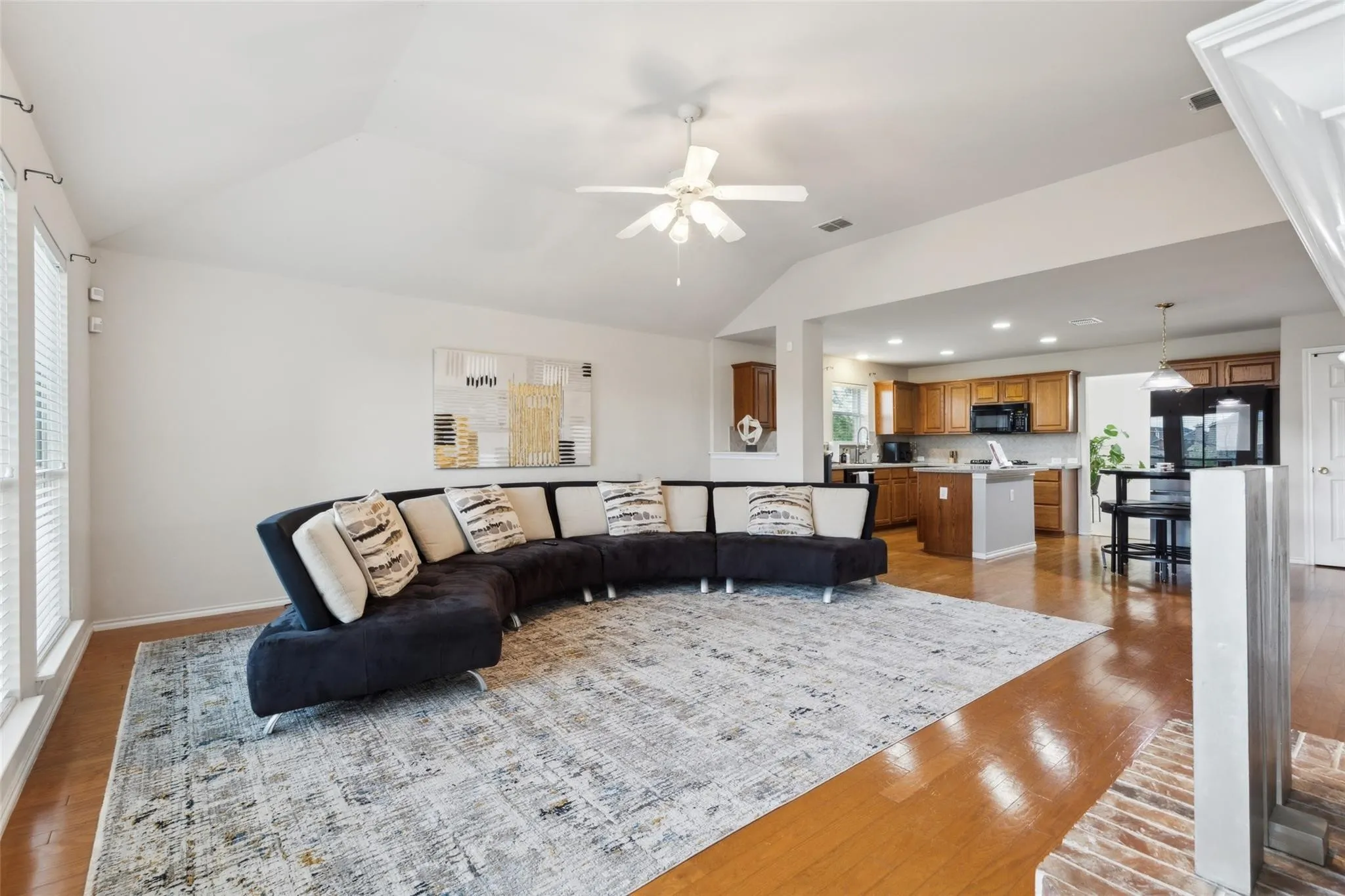 Living room featuring vaulted ceiling, ceiling fan, and dark wood-type flooring