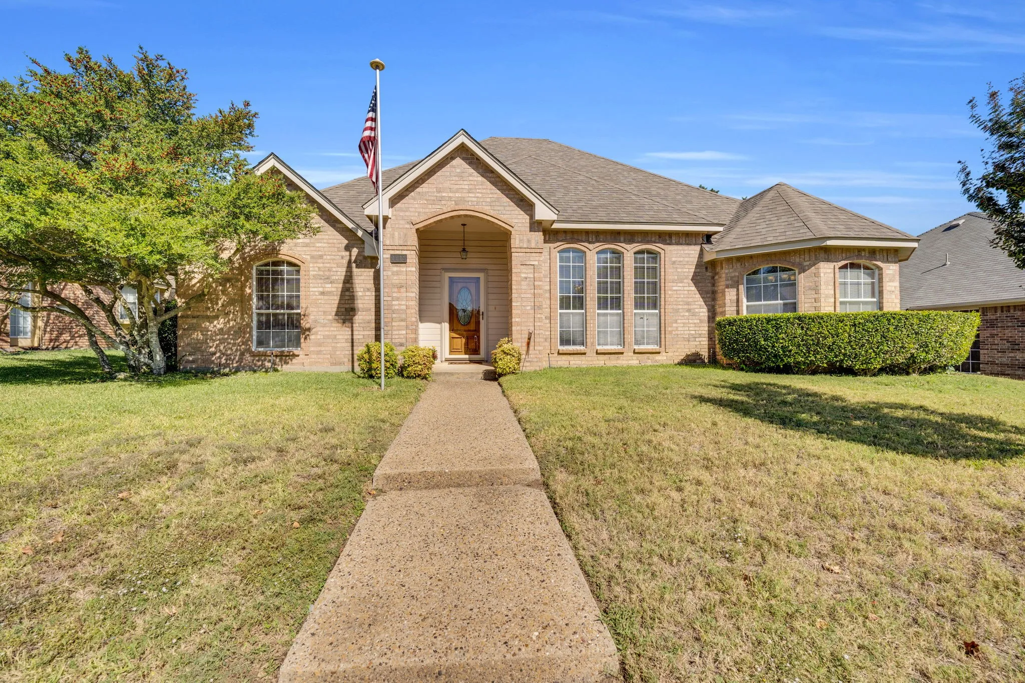 View of front of home featuring a shingled roof, brick siding, and a front yard