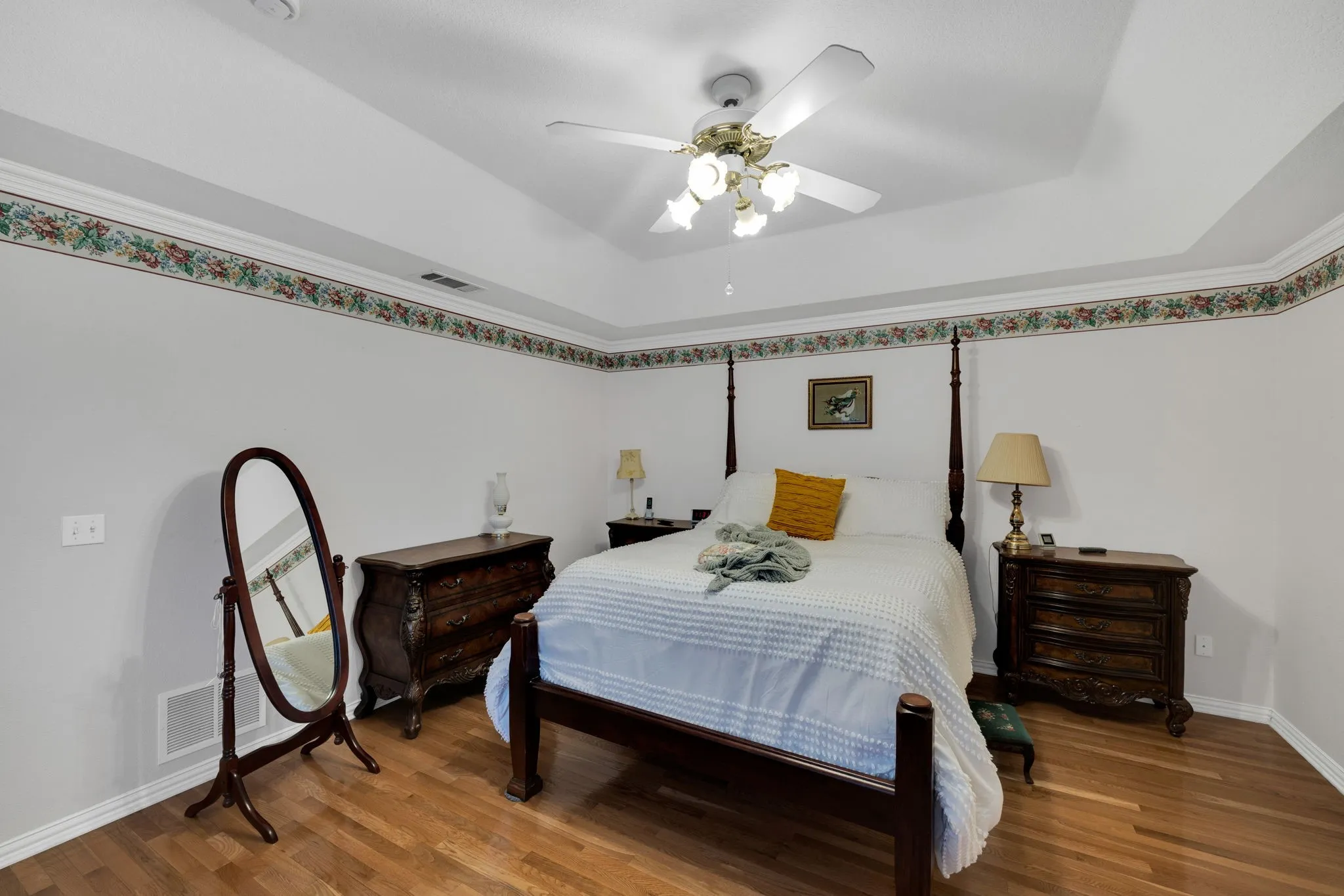 Bedroom with wood finished floors, a tray ceiling, and ceiling fan
