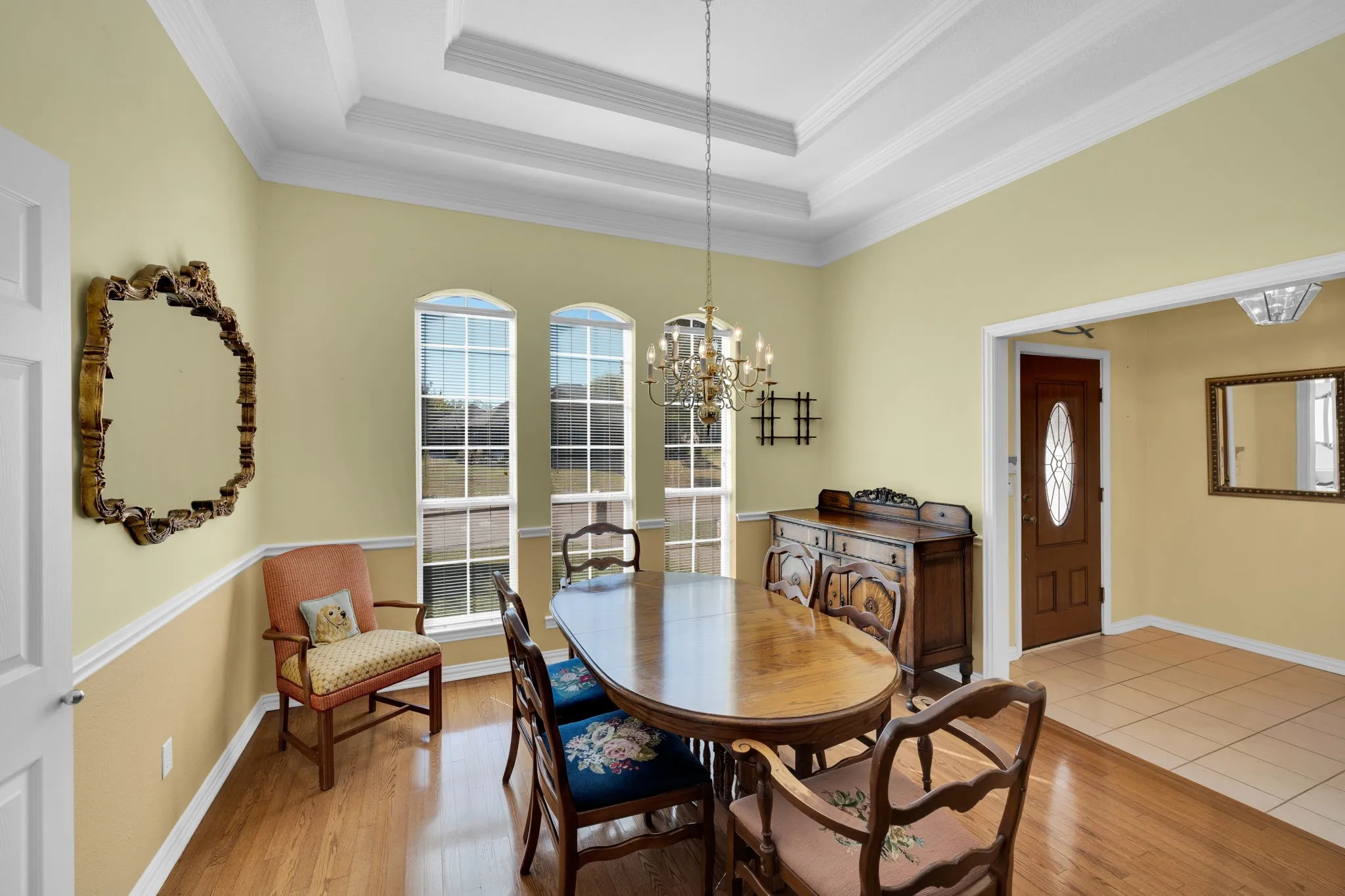 Dining room featuring a raised ceiling, a chandelier, light wood-style floors, and ornamental molding
