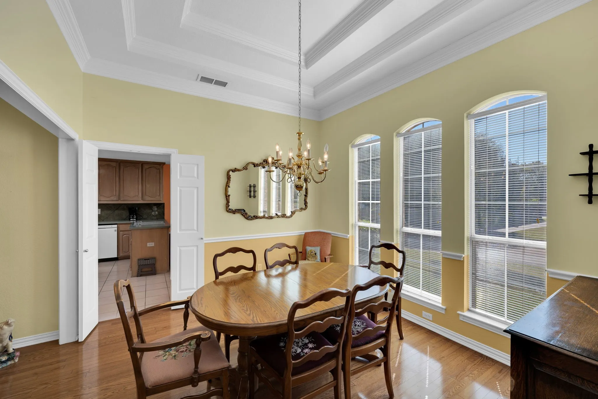 Dining space featuring light wood-style floors, a raised ceiling, a chandelier, and crown molding