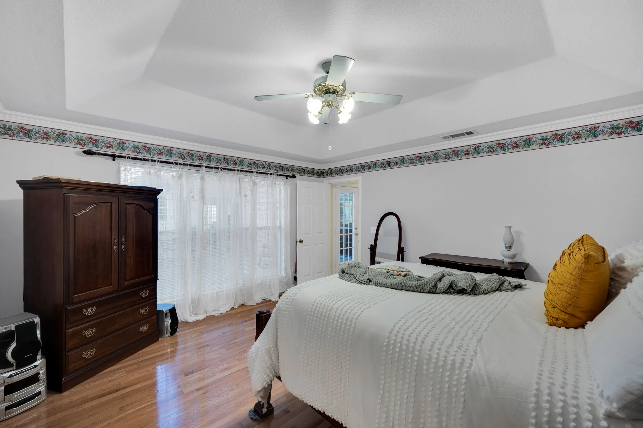 Bedroom with a raised ceiling, light wood finished floors, and ceiling​​‌​​​​‌​​‌‌​‌‌​​​‌‌​‌​‌​‌​​​‌​​ fan