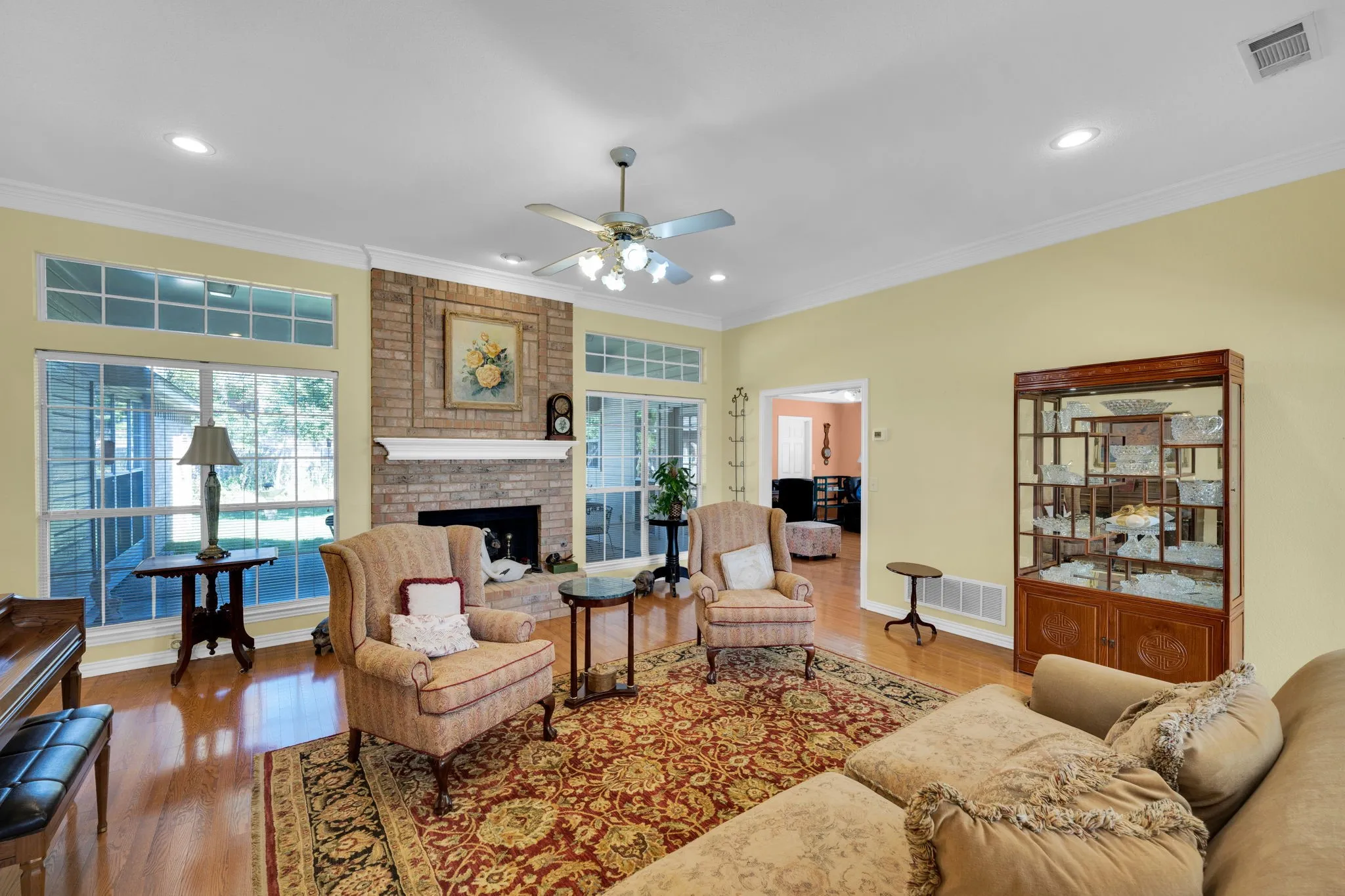 Living room featuring crown molding, wood finished floors, a fireplace, recessed lighting, and ceiling fan