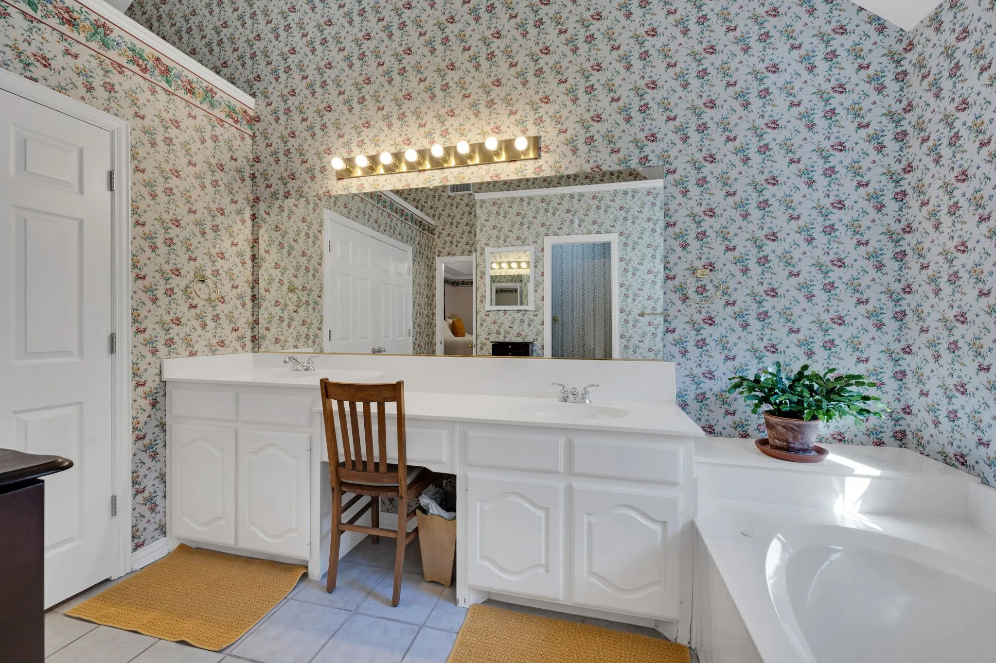 Bathroom with double vanity, light tile patterned flooring, and a garden tub