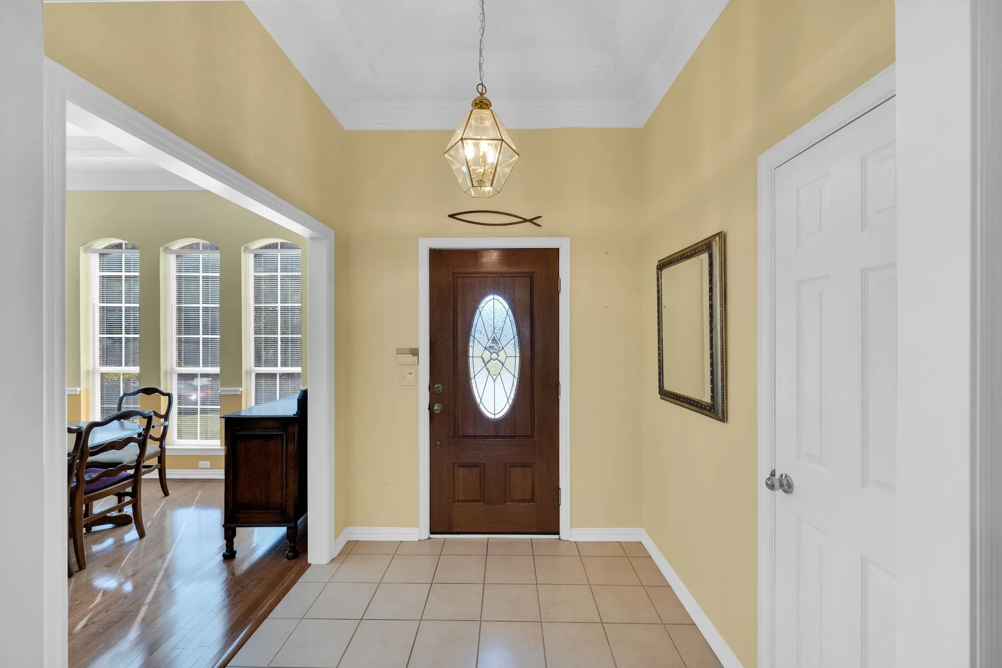 Entrance foyer featuring crown molding, light tile patterned floors, and a chandelier