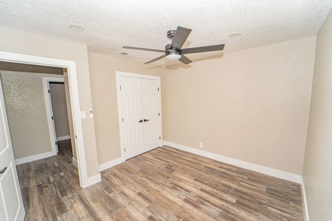 Unfurnished bedroom with a textured ceiling, wood finished floors, a closet, and a ceiling fan