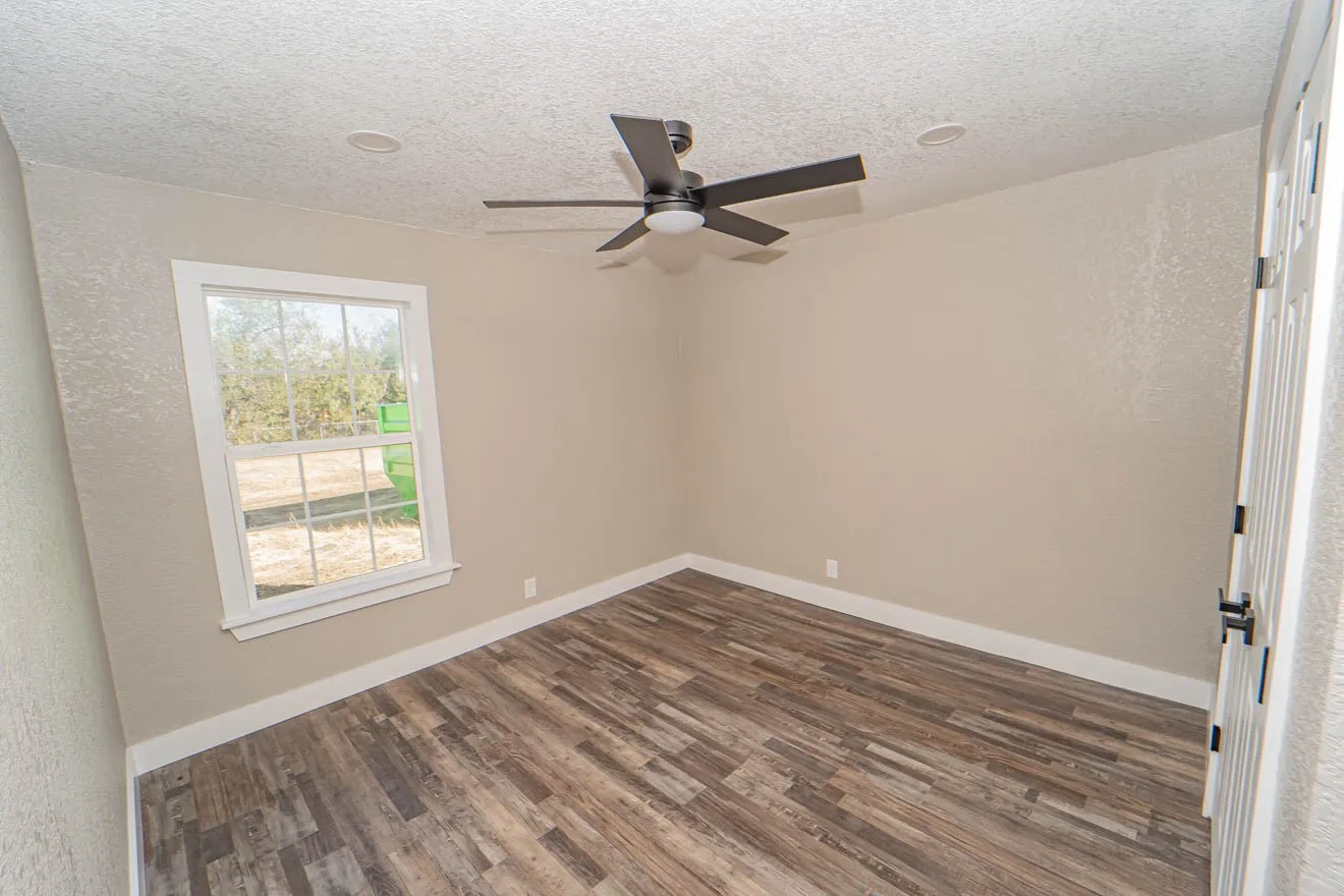 Empty room featuring a textured ceiling, dark wood finished floors, ceiling fan, and a textured wall