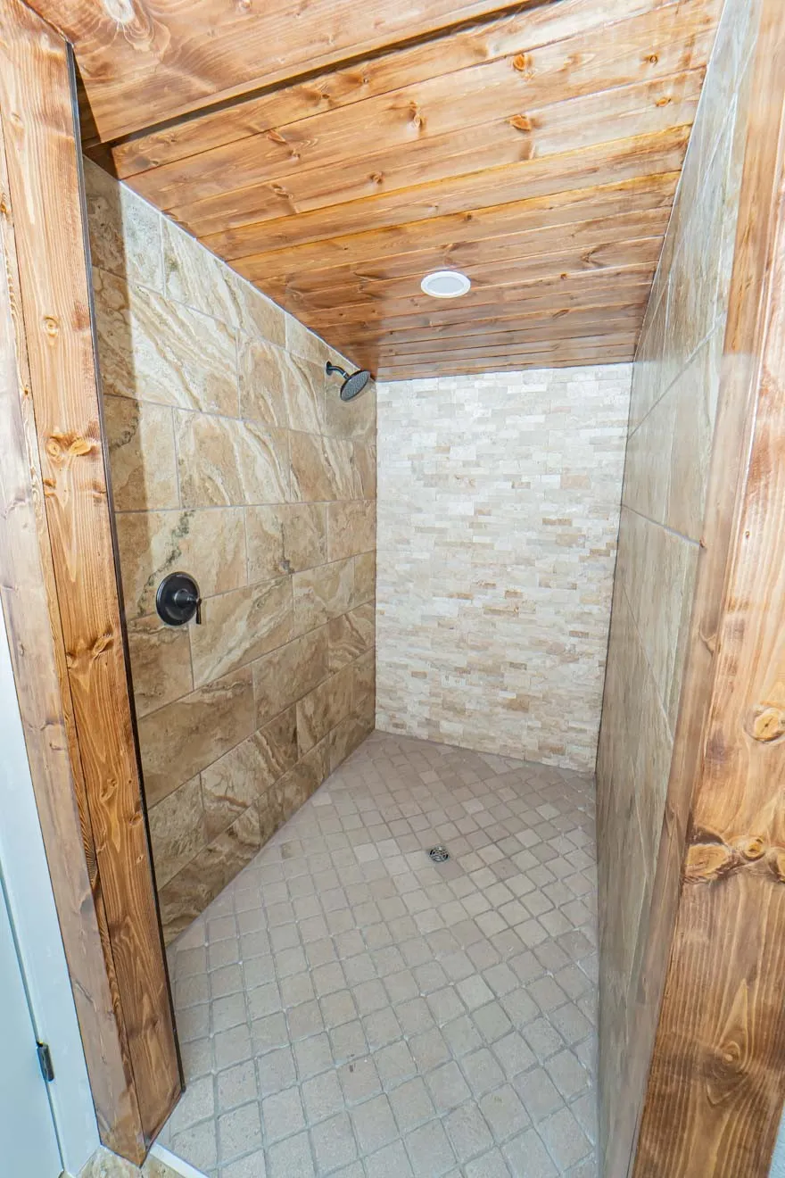 Bathroom with a shower stall, wood ceiling, and tile patterned flooring
