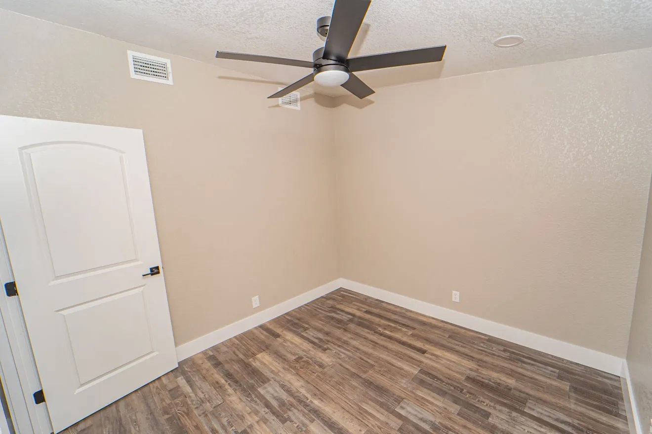 Unfurnished room with a textured ceiling, a textured wall, dark wood finished floors, and a ceiling fan