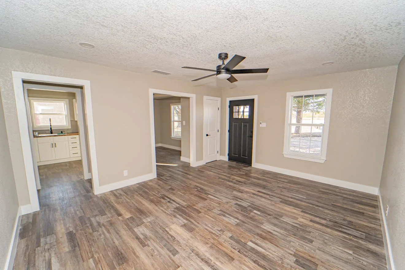 Unfurnished living room featuring a textured ceiling, dark wood-style floors, and ceiling fan