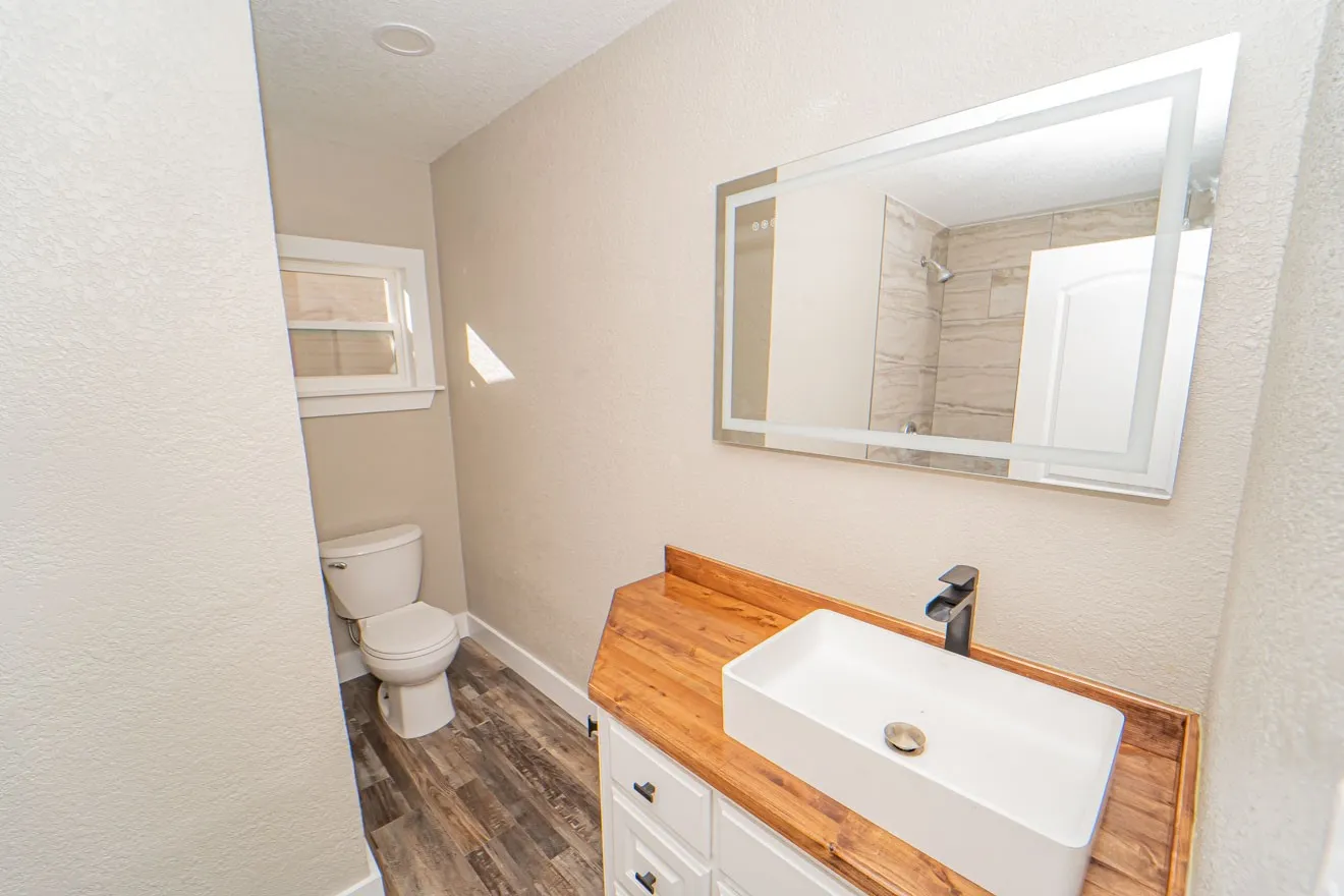 Full bath with a textured wall, vanity, dark wood-type flooring, a textured ceiling, and a shower
