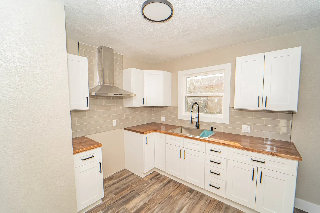 Kitchen with wood counters, wall chimney exhaust hood, a textured ceiling, light wood-type flooring, and white cabinetry