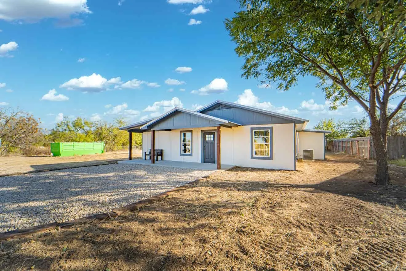 View of front of home with gravel driveway and a patio
