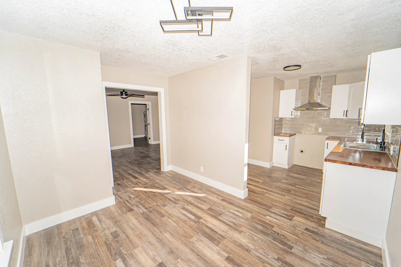 Kitchen featuring white cabinets, decorative backsplash, a textured ceiling, wall chimney exhaust hood, and light wood-type flooring