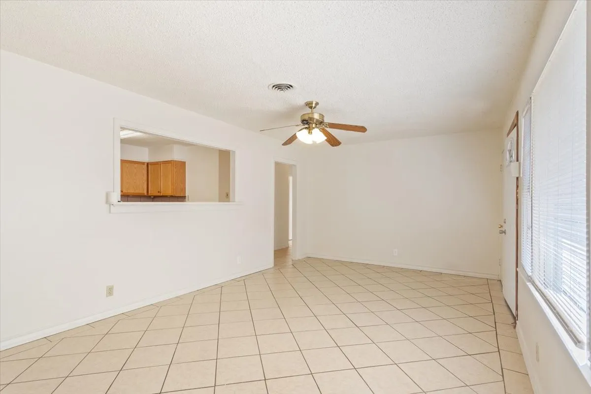 Unfurnished room featuring a textured ceiling, light tile patterned floors, and ceiling fan