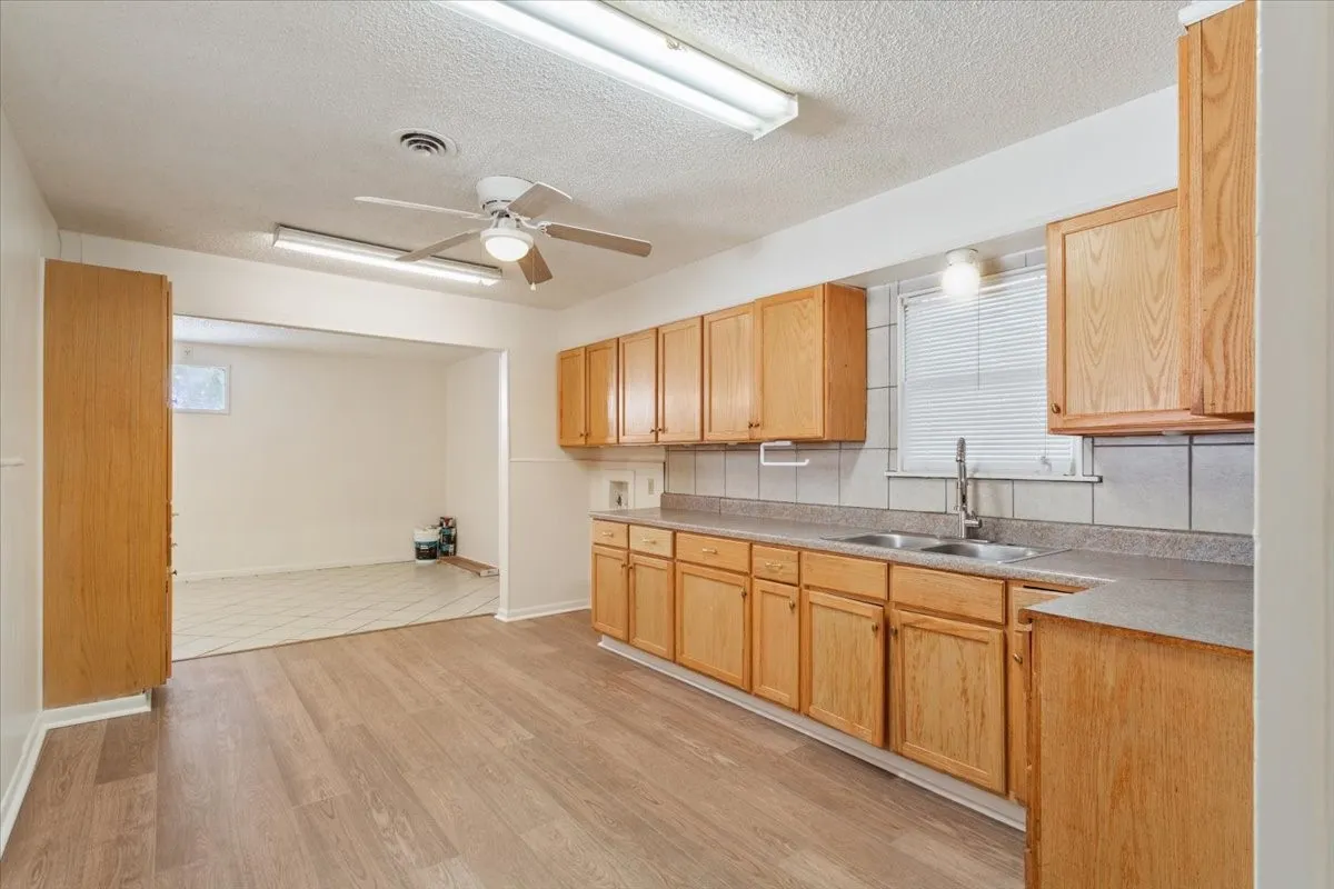 Kitchen featuring light countertops, a textured ceiling, a ceiling fan, light brown cabinetry, and light wood-type flooring