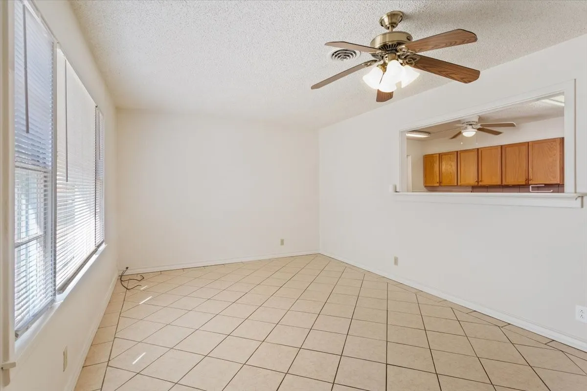 Spare room featuring a textured ceiling, light tile patterned floors, and a ceiling fan