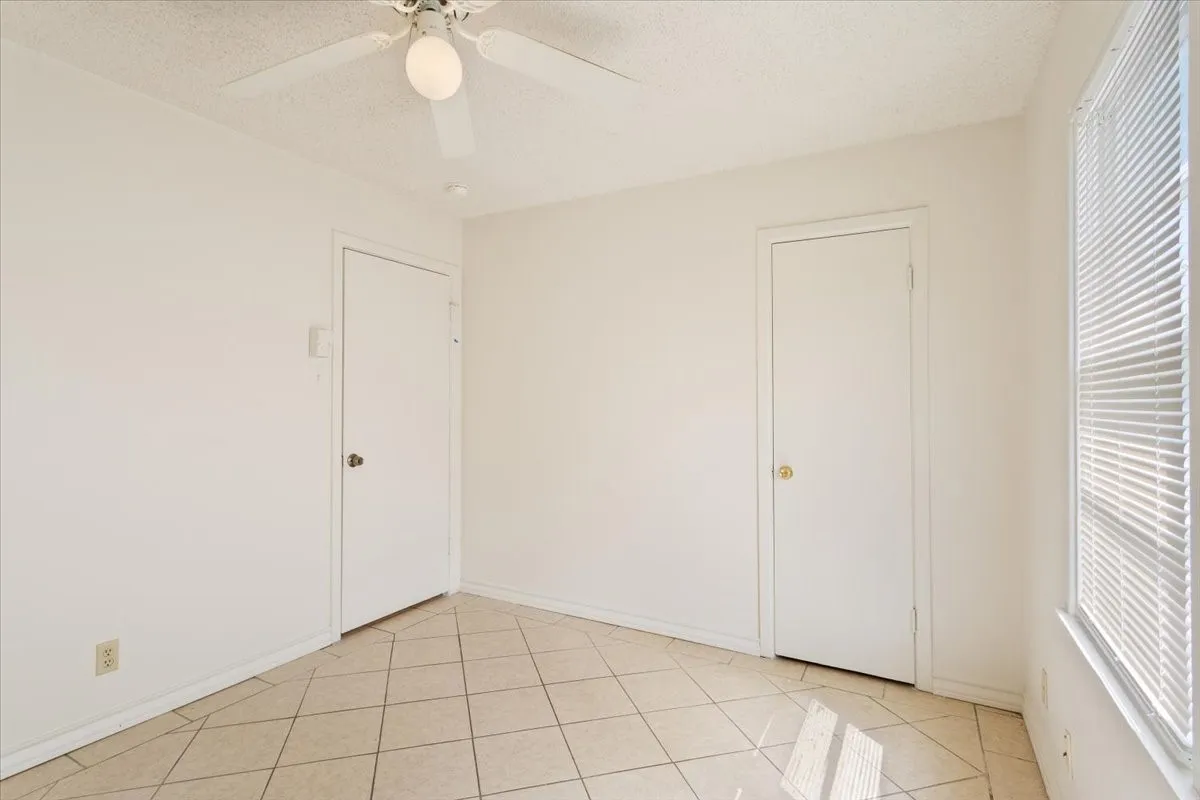 Unfurnished bedroom with a ceiling fan, light tile patterned flooring, and a textured ceiling