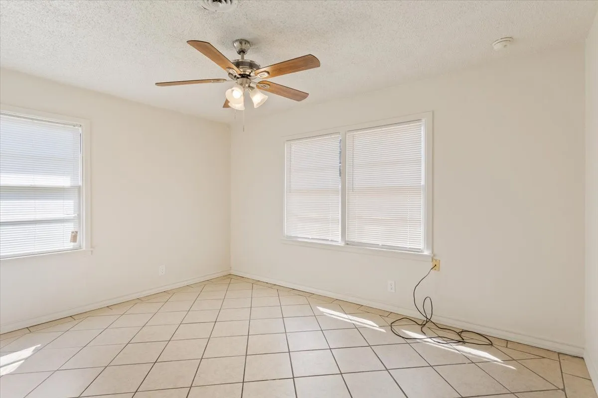 Unfurnished room with a textured ceiling, light tile patterned flooring, and a ceiling fan
