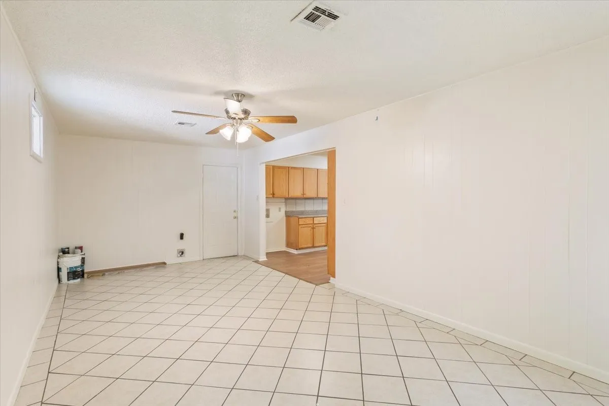 Unfurnished room featuring ceiling fan, light tile patterned flooring, and a textured ceiling