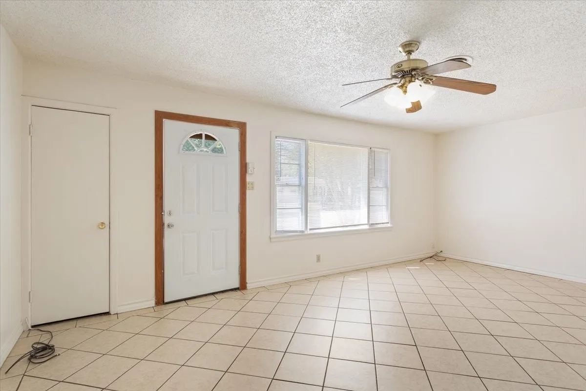 Foyer entrance featuring a textured ceiling, ceiling fan, and light tile patterned floors