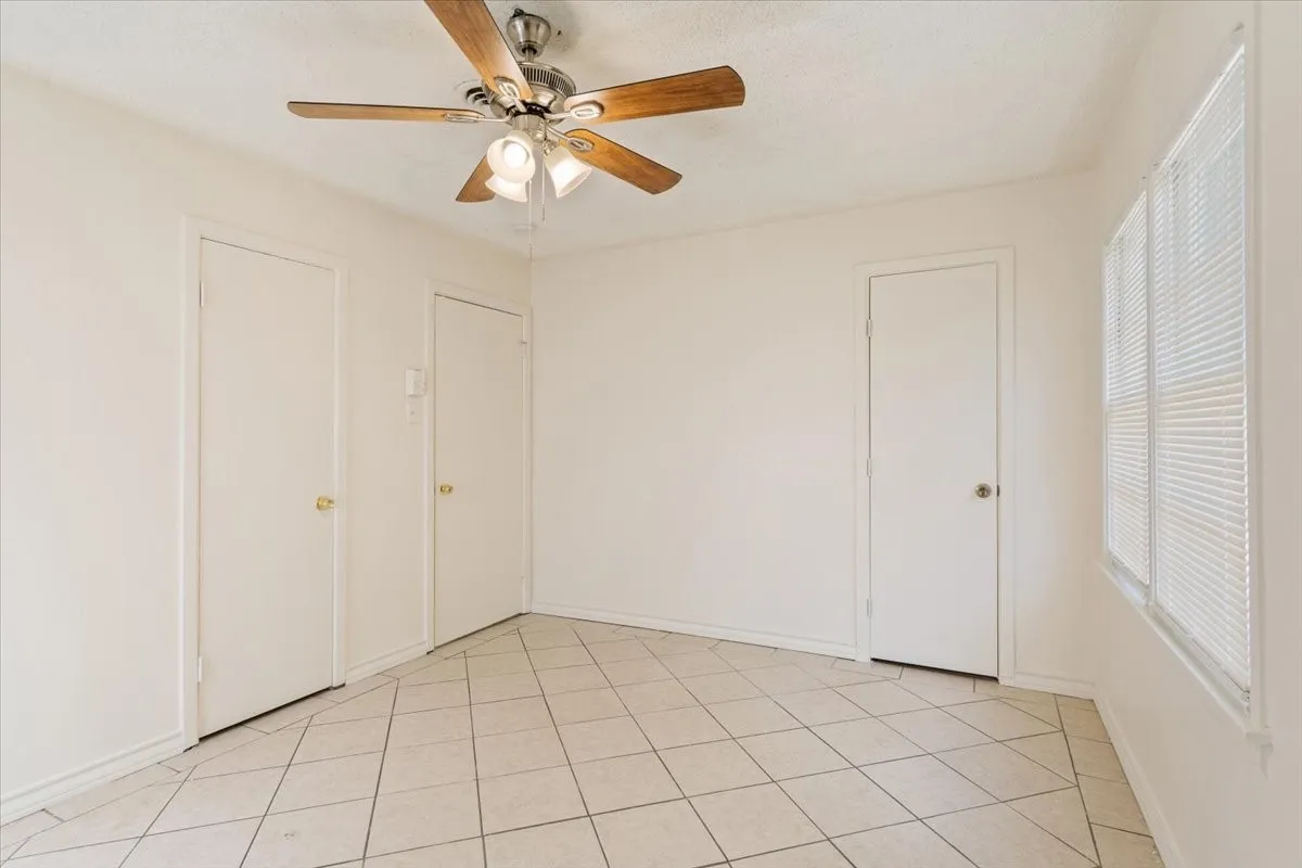 Unfurnished bedroom with light tile patterned floors and a ceiling fan