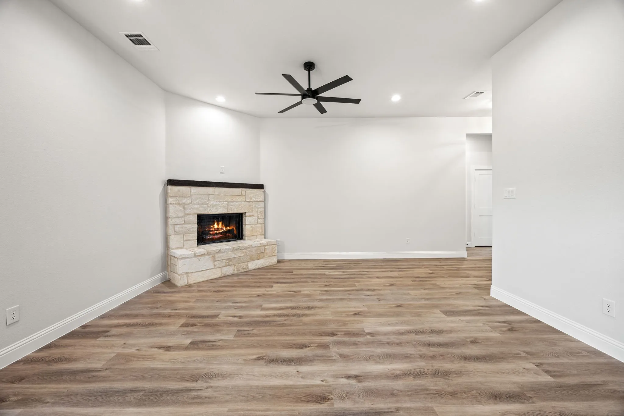 Unfurnished living room featuring a stone fireplace, light wood-style flooring, recessed lighting, and ceiling fan