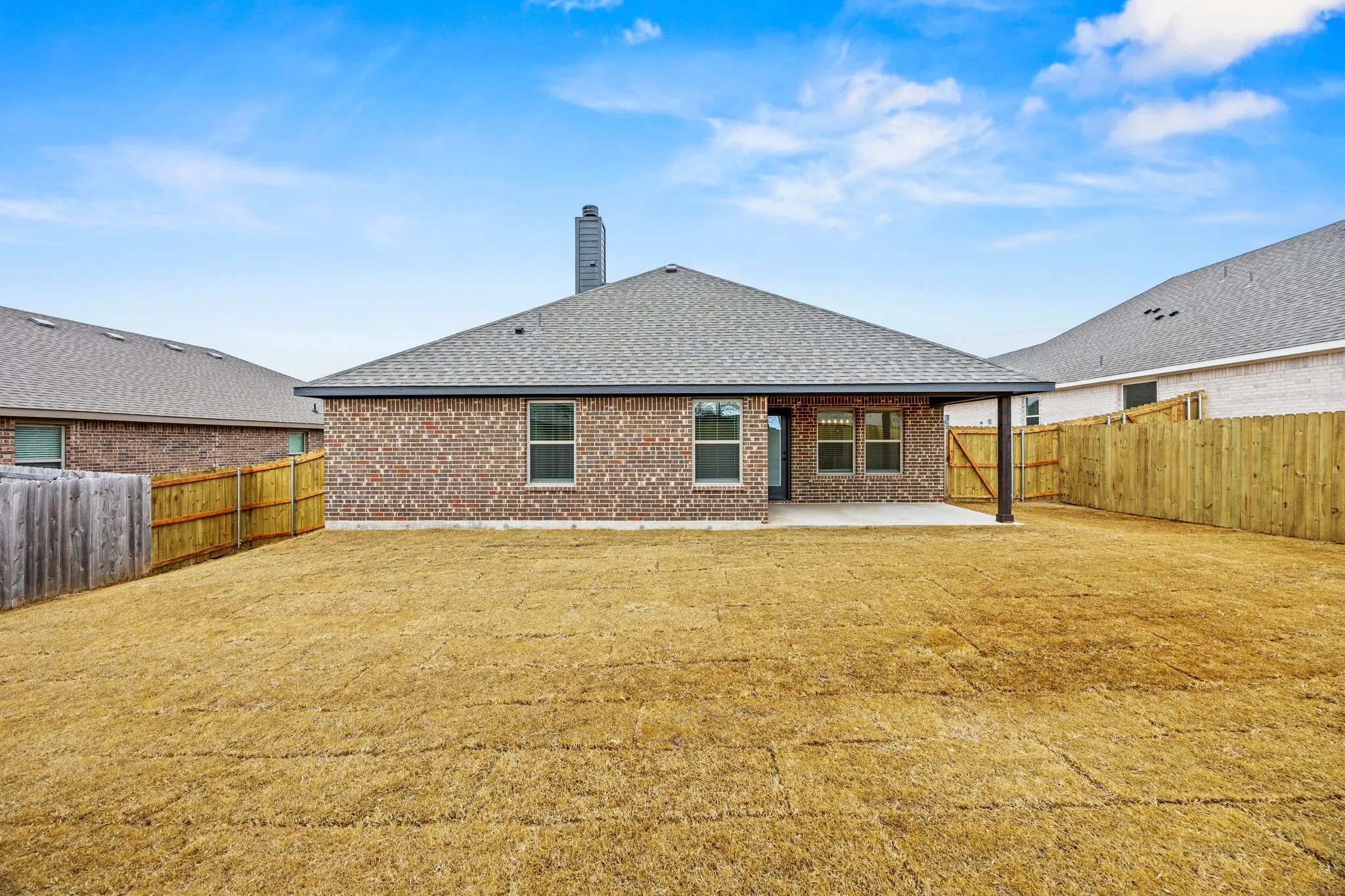 Back of house featuring brick siding, a patio, a chimney, and a fenced backyard