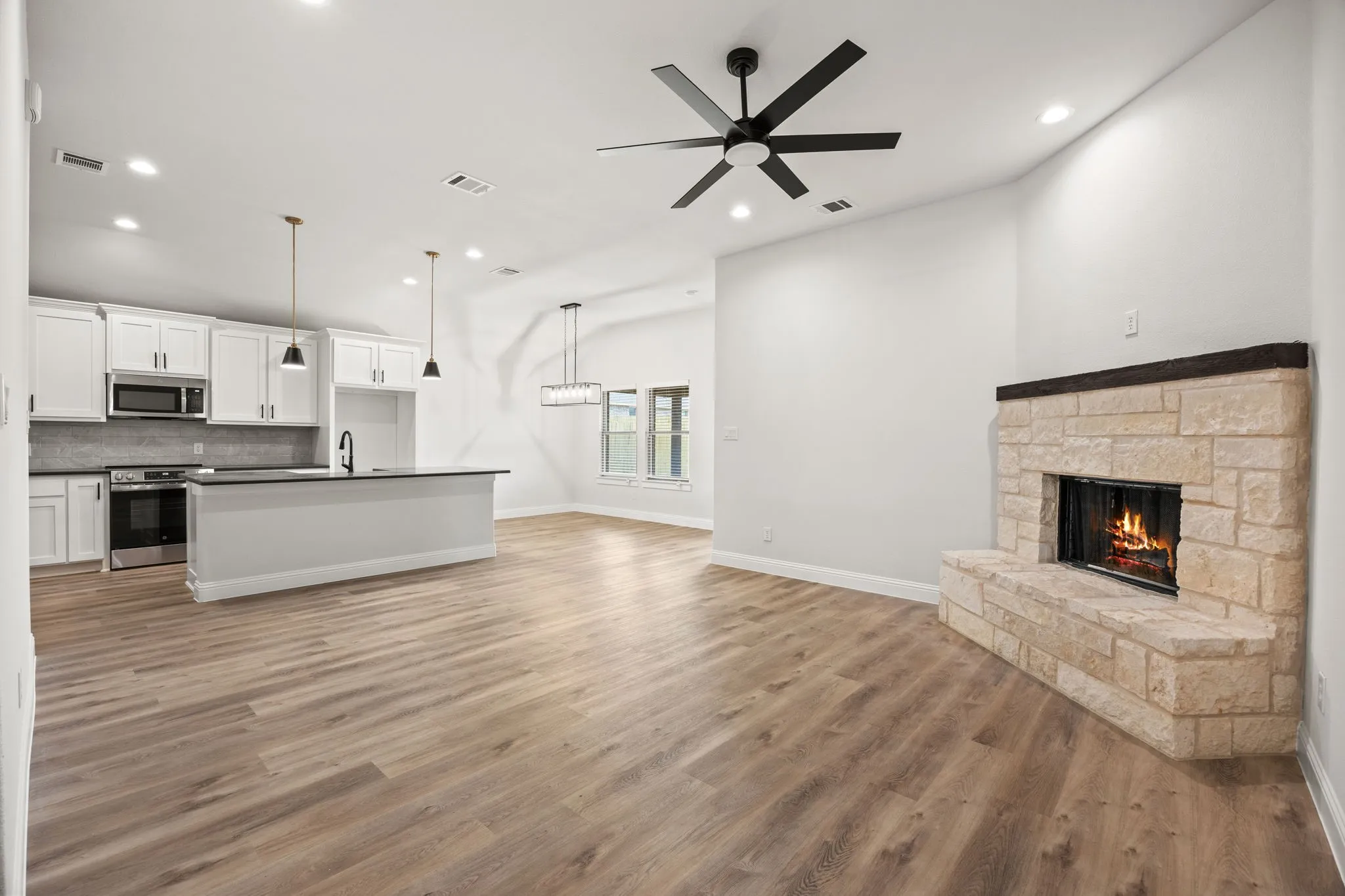 Unfurnished living room featuring a stone fireplace, light wood finished floors, recessed lighting, and ceiling fan