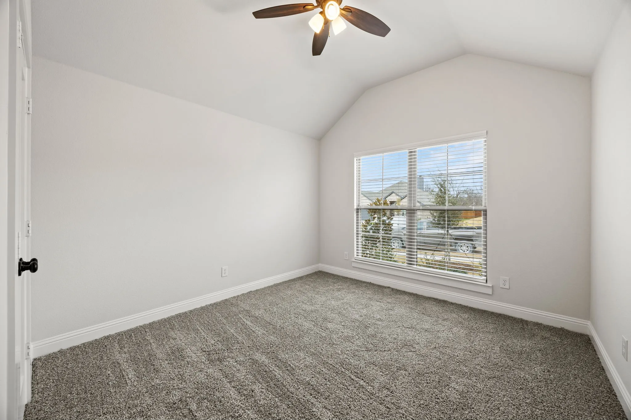 Empty room featuring ceiling fan, carpet floors, and vaulted ceiling