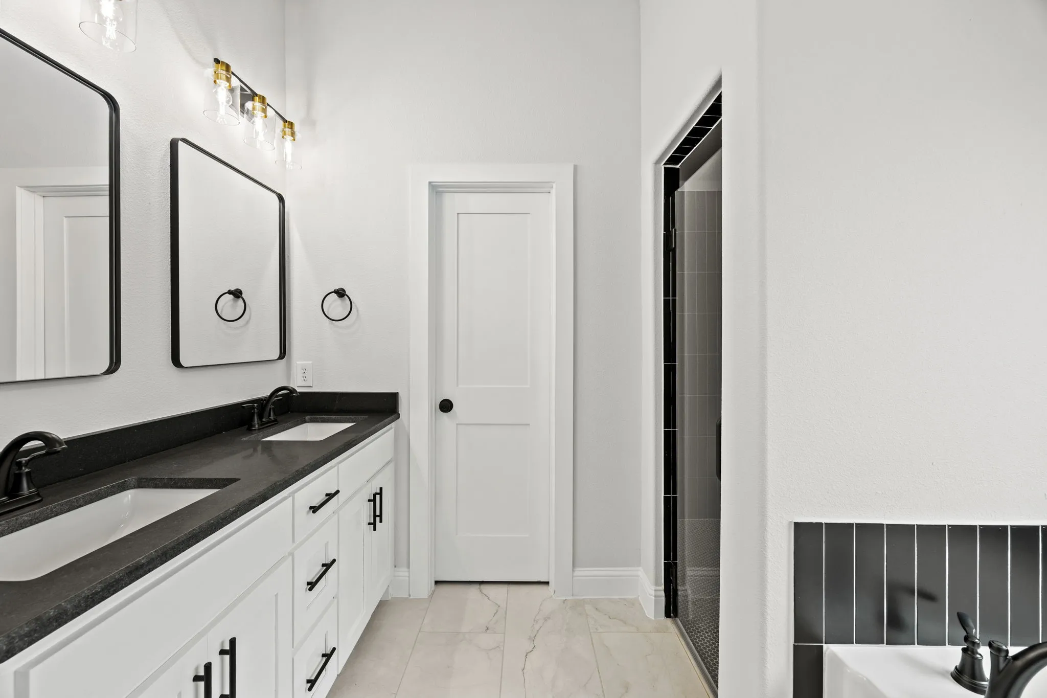 Full bathroom with double vanity, light marble finish floors, and a tub