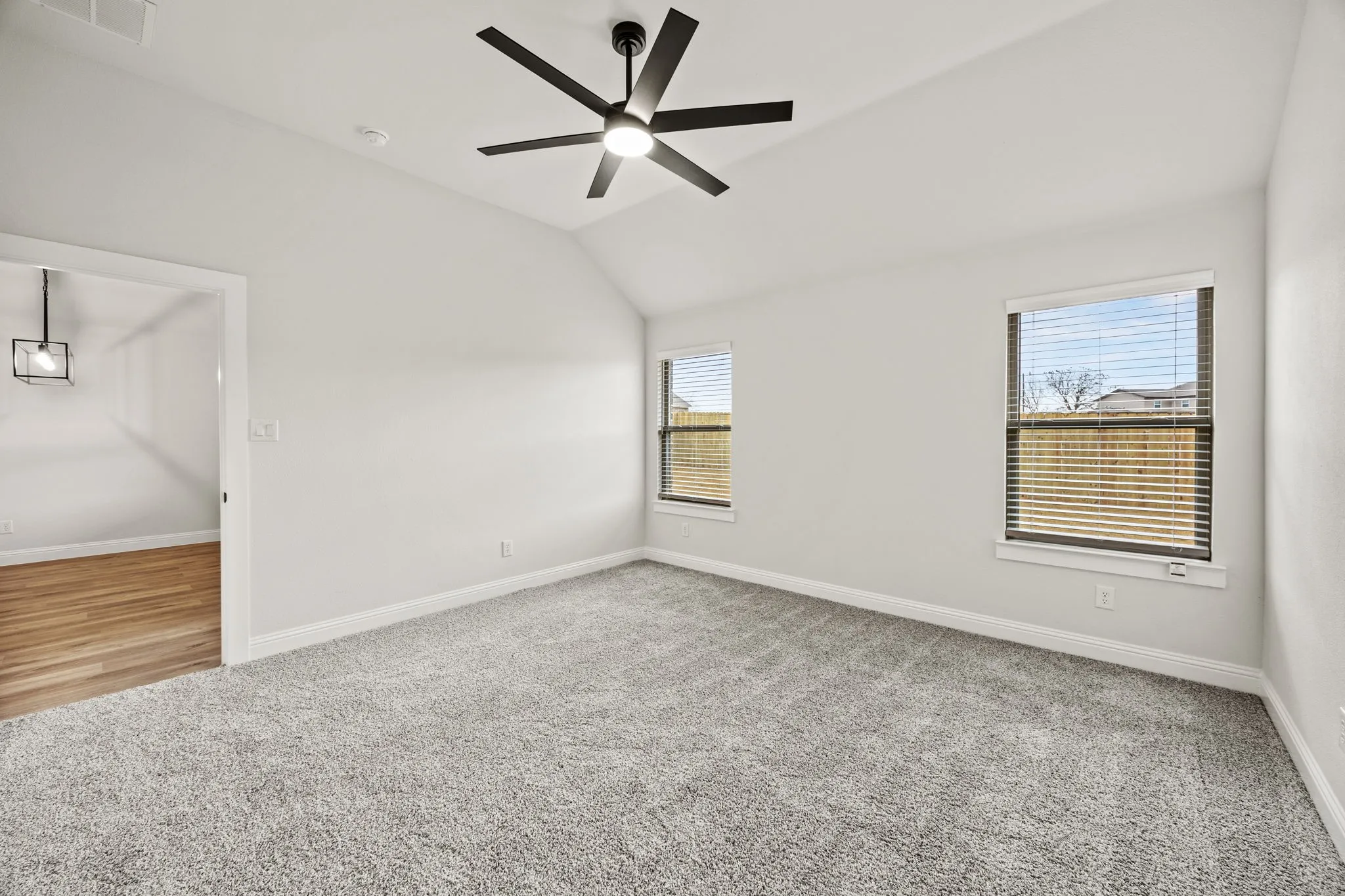 Empty room featuring light carpet, lofted ceiling, and a ceiling fan