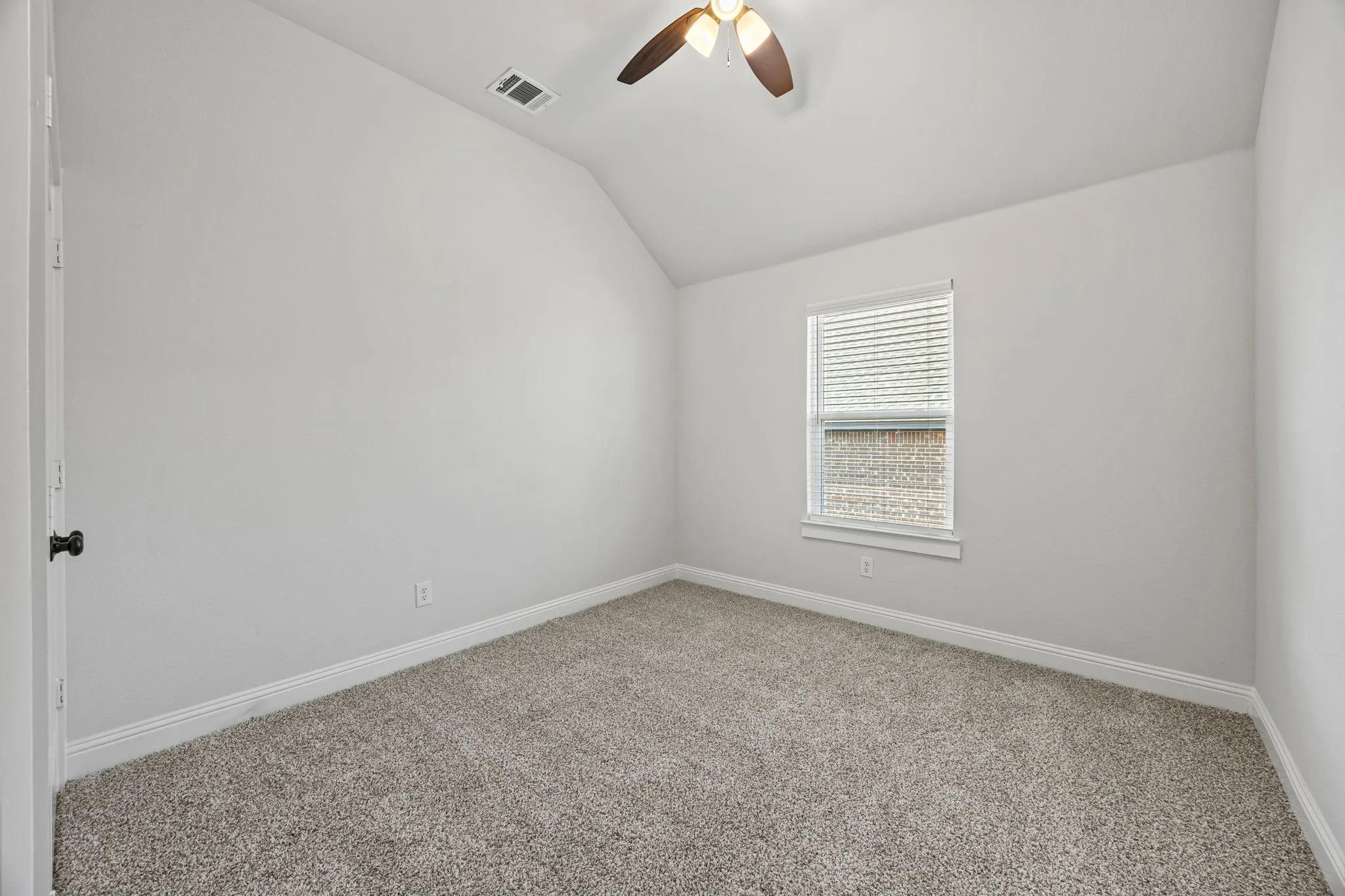 Empty room with carpet flooring, vaulted ceiling, and ceiling fan