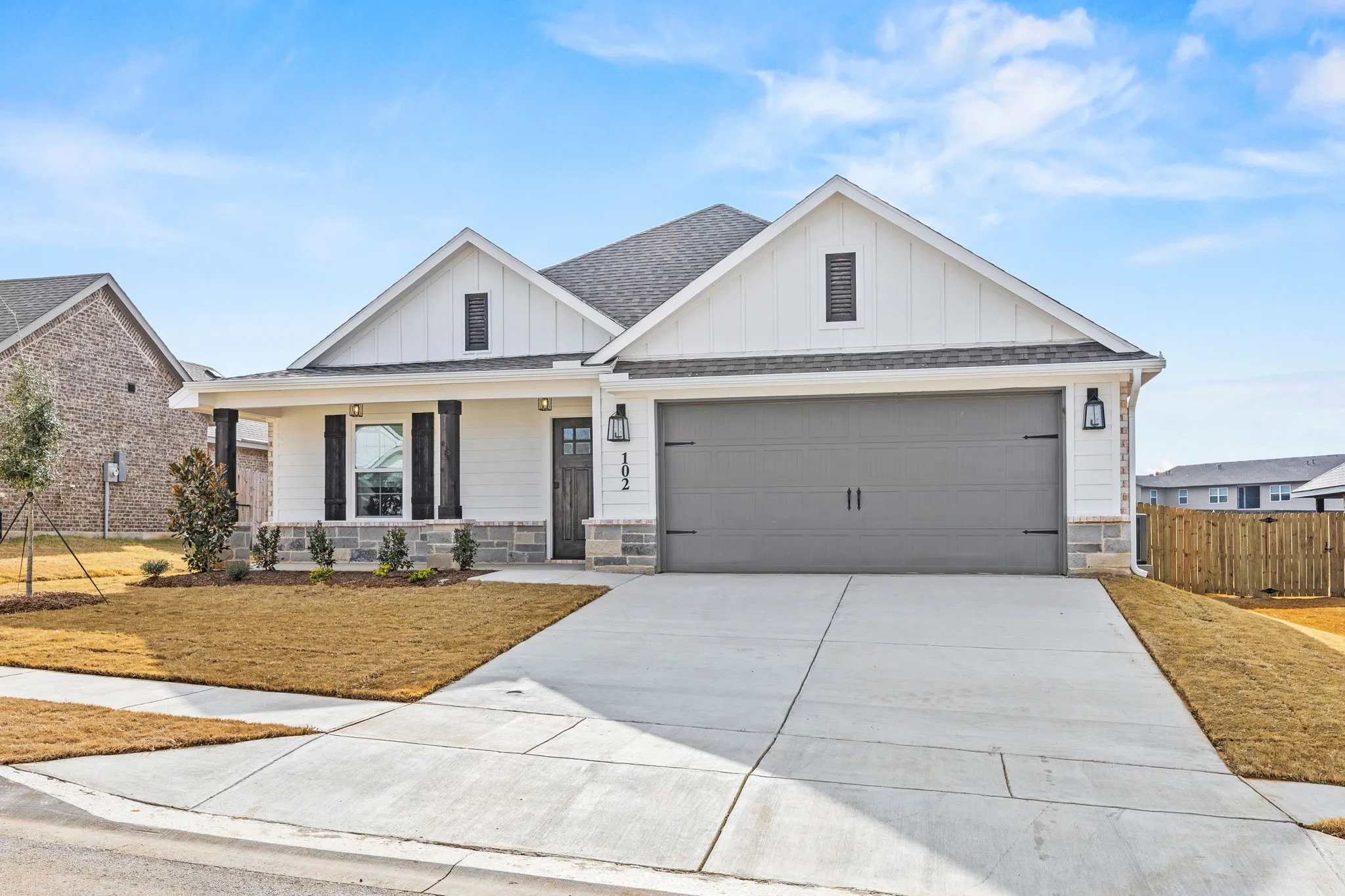 Modern farmhouse style home featuring board and batten siding, a porch, driveway, a shingled roof, and an attached garage