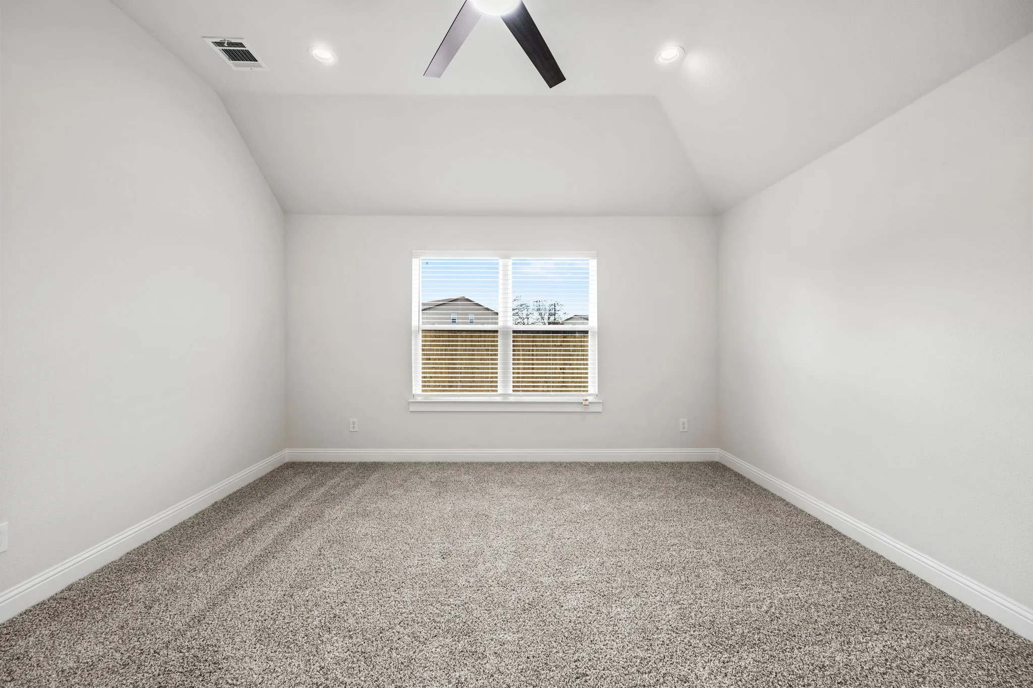 Spare room featuring light colored carpet, vaulted ceiling, ceiling fan, and recessed lighting
