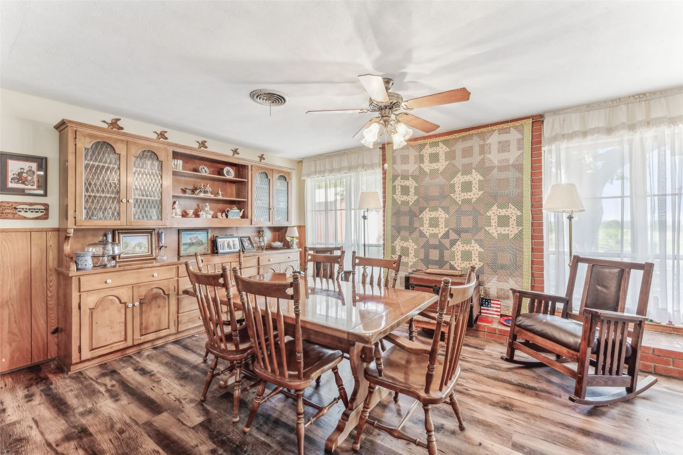 Dining space with dark wood finished floors, a ceiling fan, and wood walls