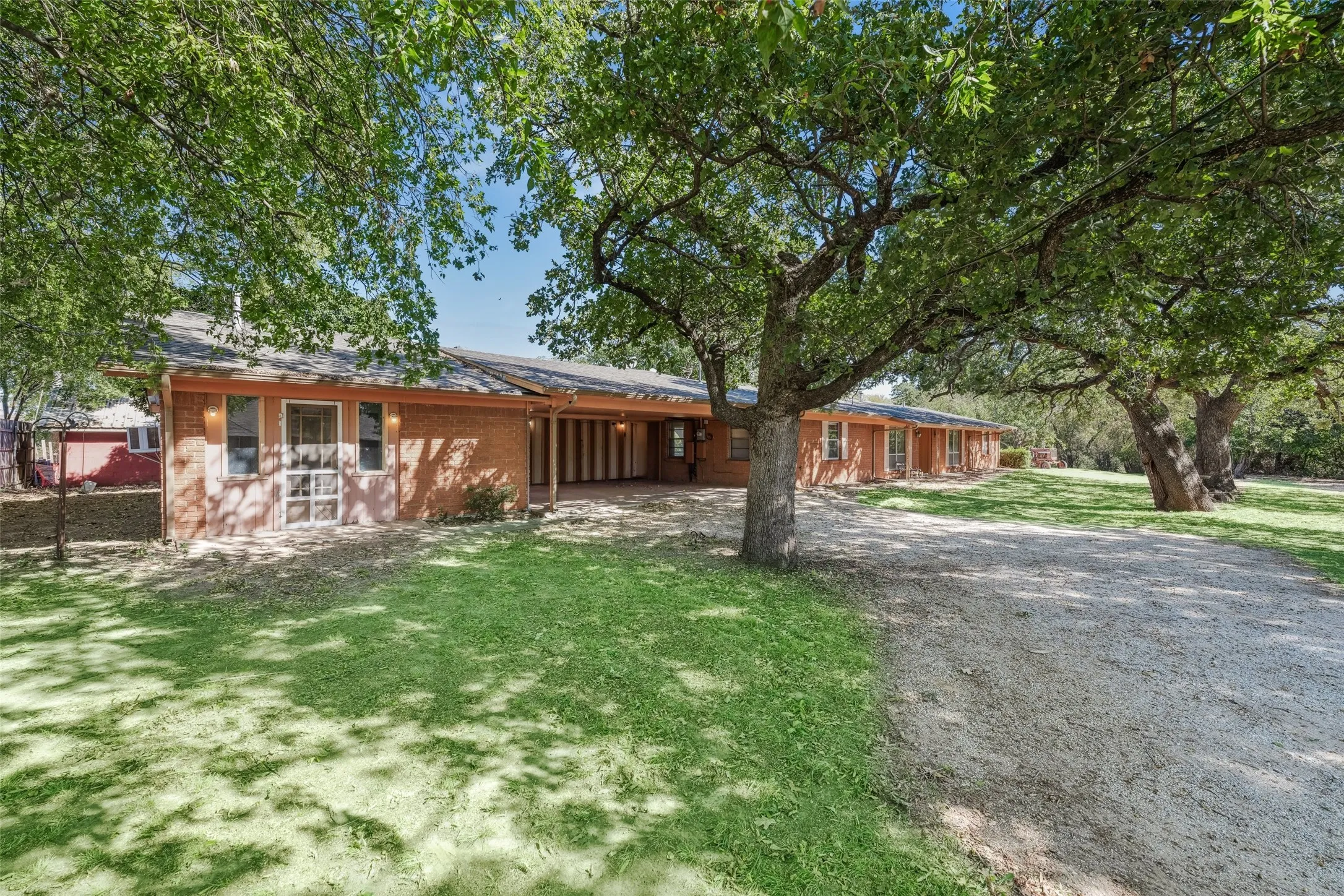 Ranch-style house with a carport, driveway, brick siding, and a front yard