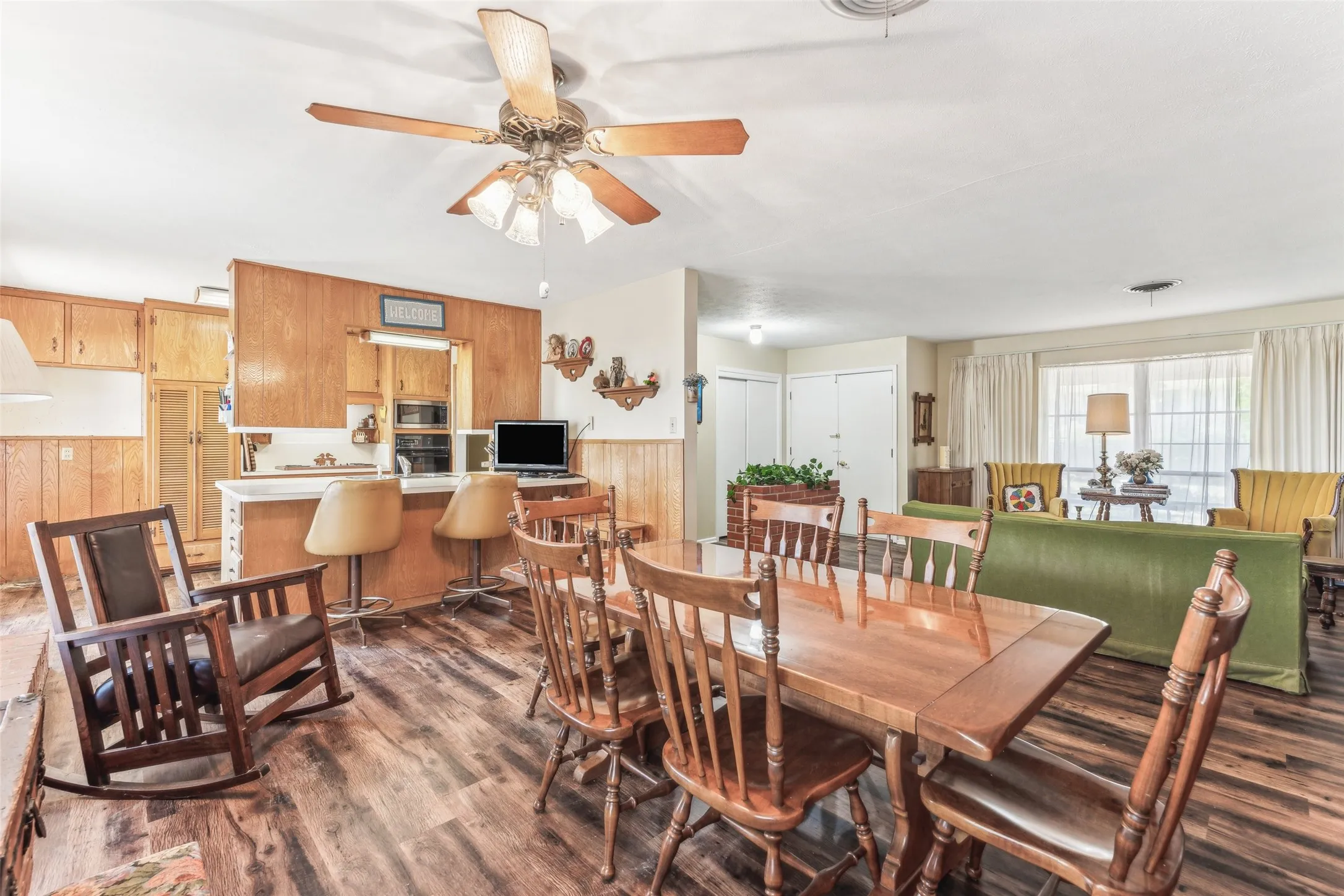 Dining space with dark wood finished floors, wooden walls, and ceiling fan