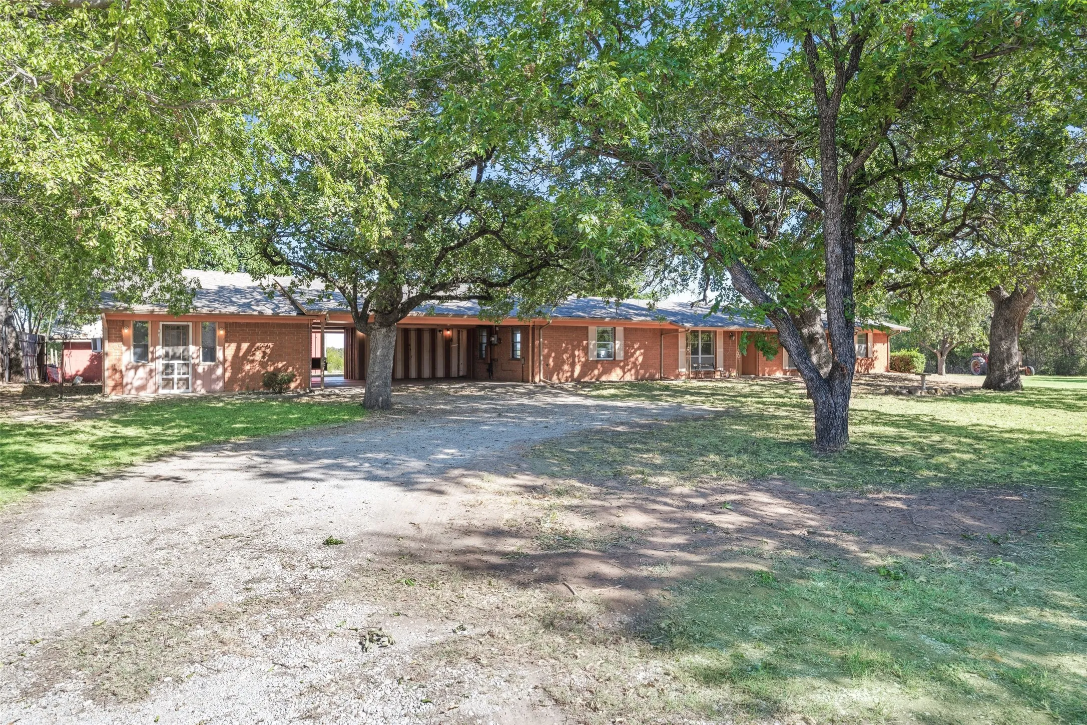 Ranch-style home featuring dirt driveway and a front lawn
