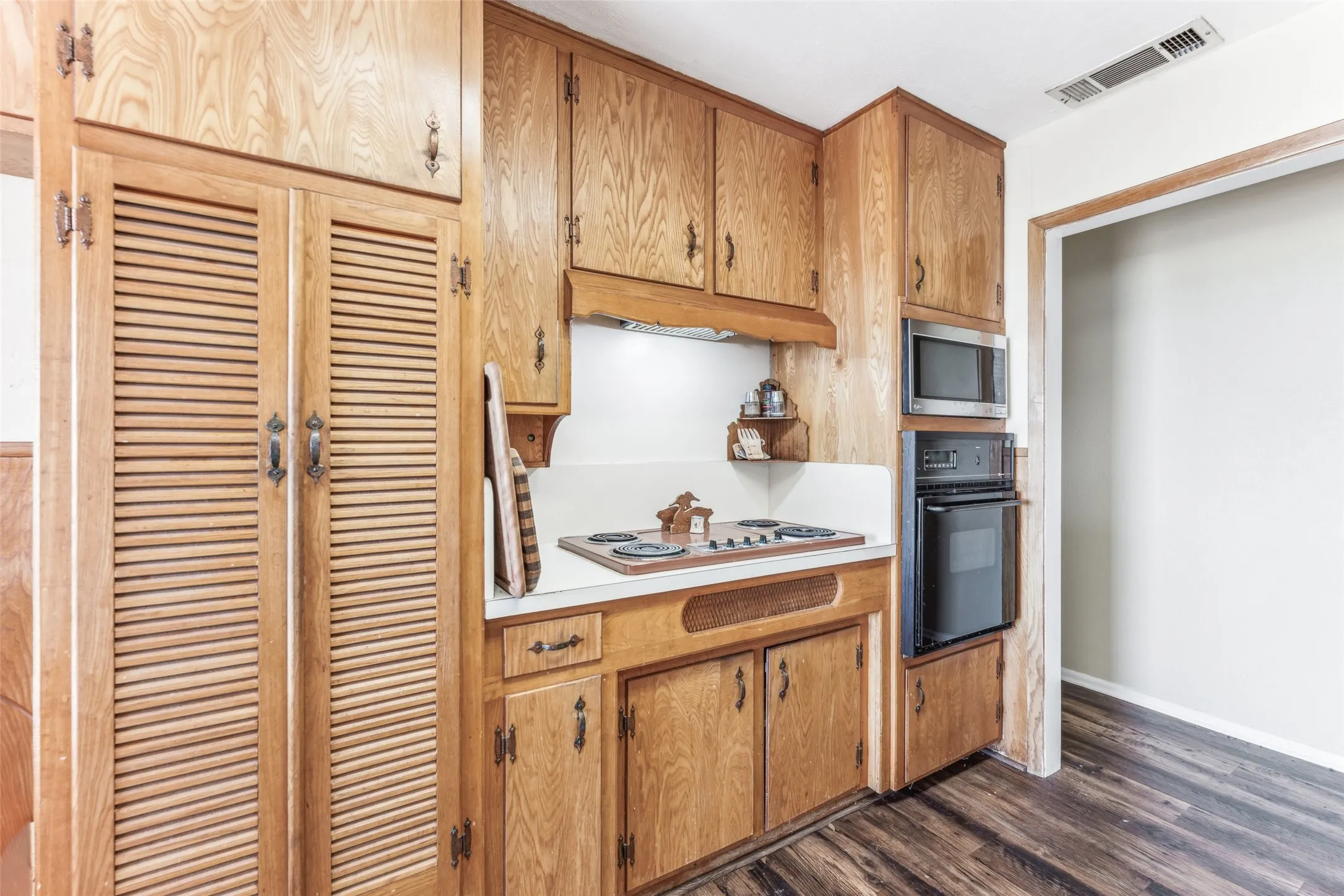 Kitchen with light countertops, stainless steel appliances, dark wood-style floors, and brown cabinetry