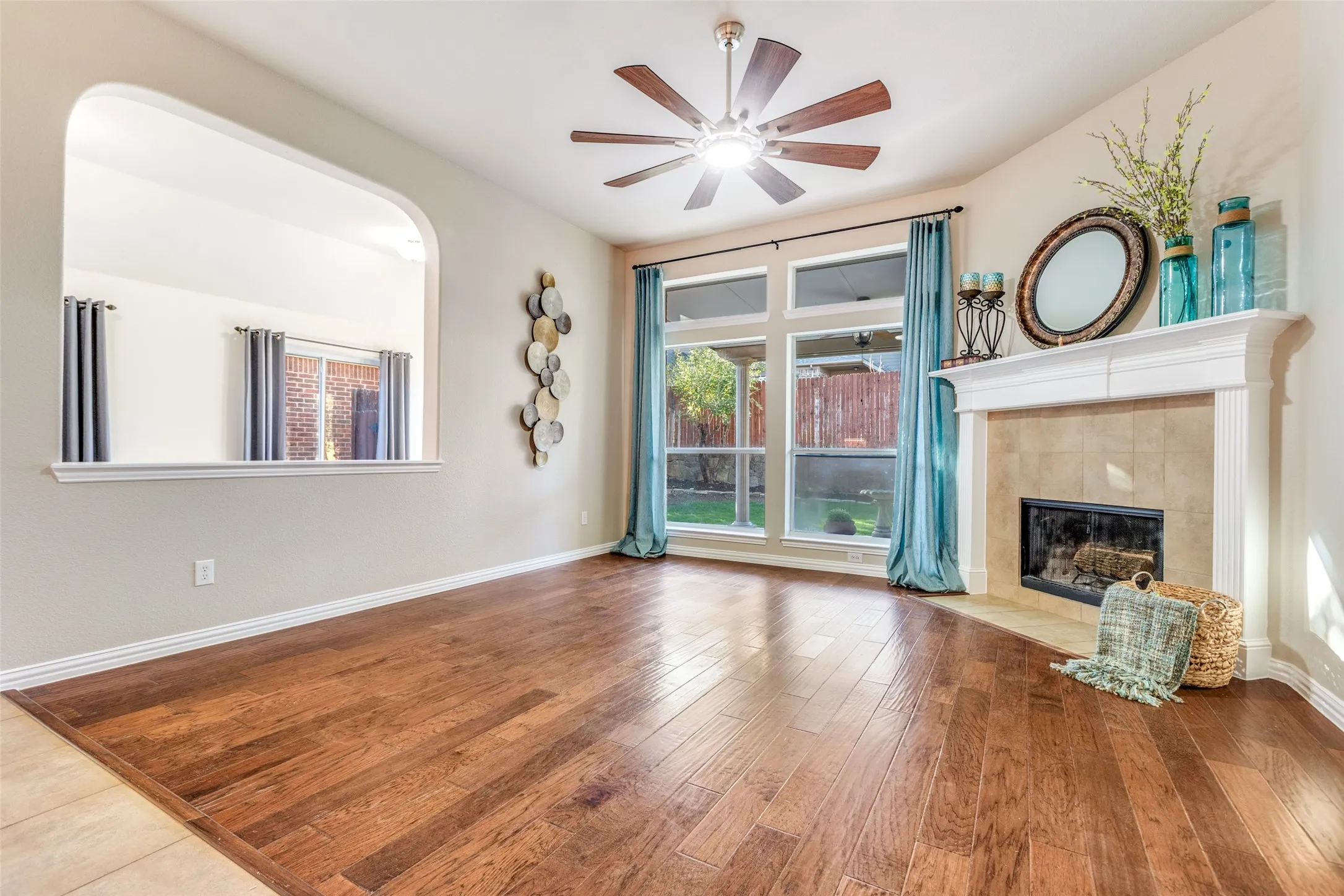 Living room with a ceiling fan, hardwood / wood-style floors, and a tiled fireplace